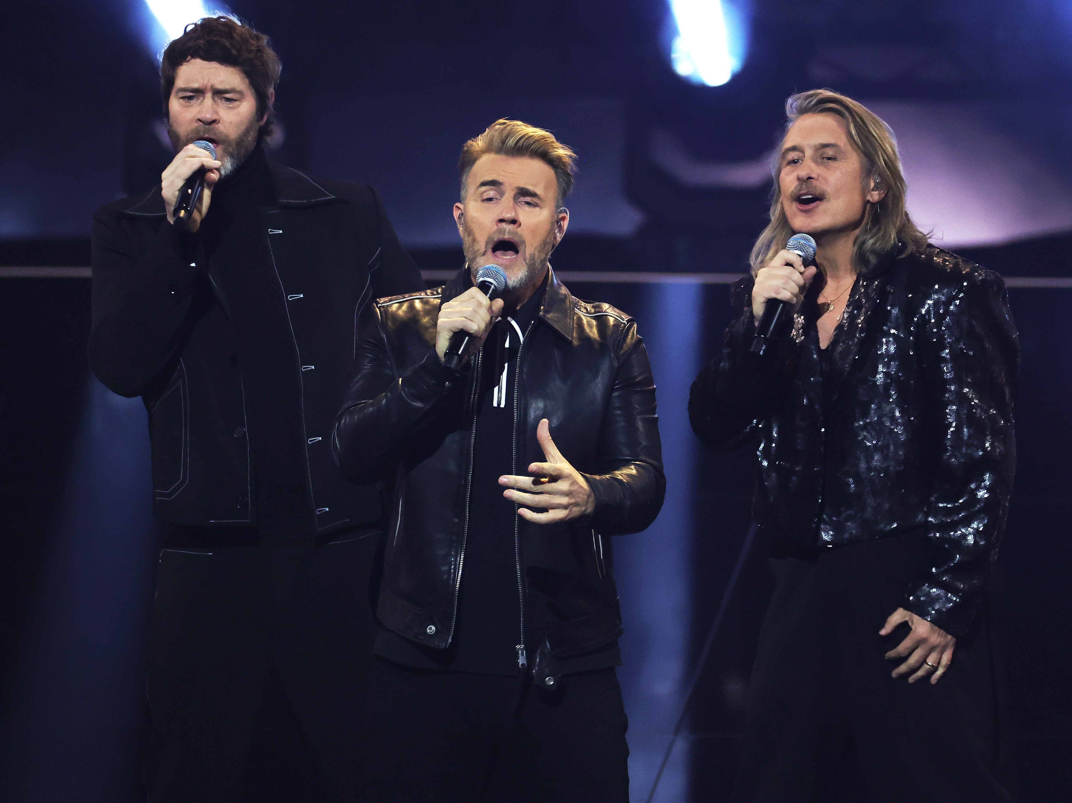 Howard Donald, Gary Barlow e Mark Owen do Take That se apresentam no palco