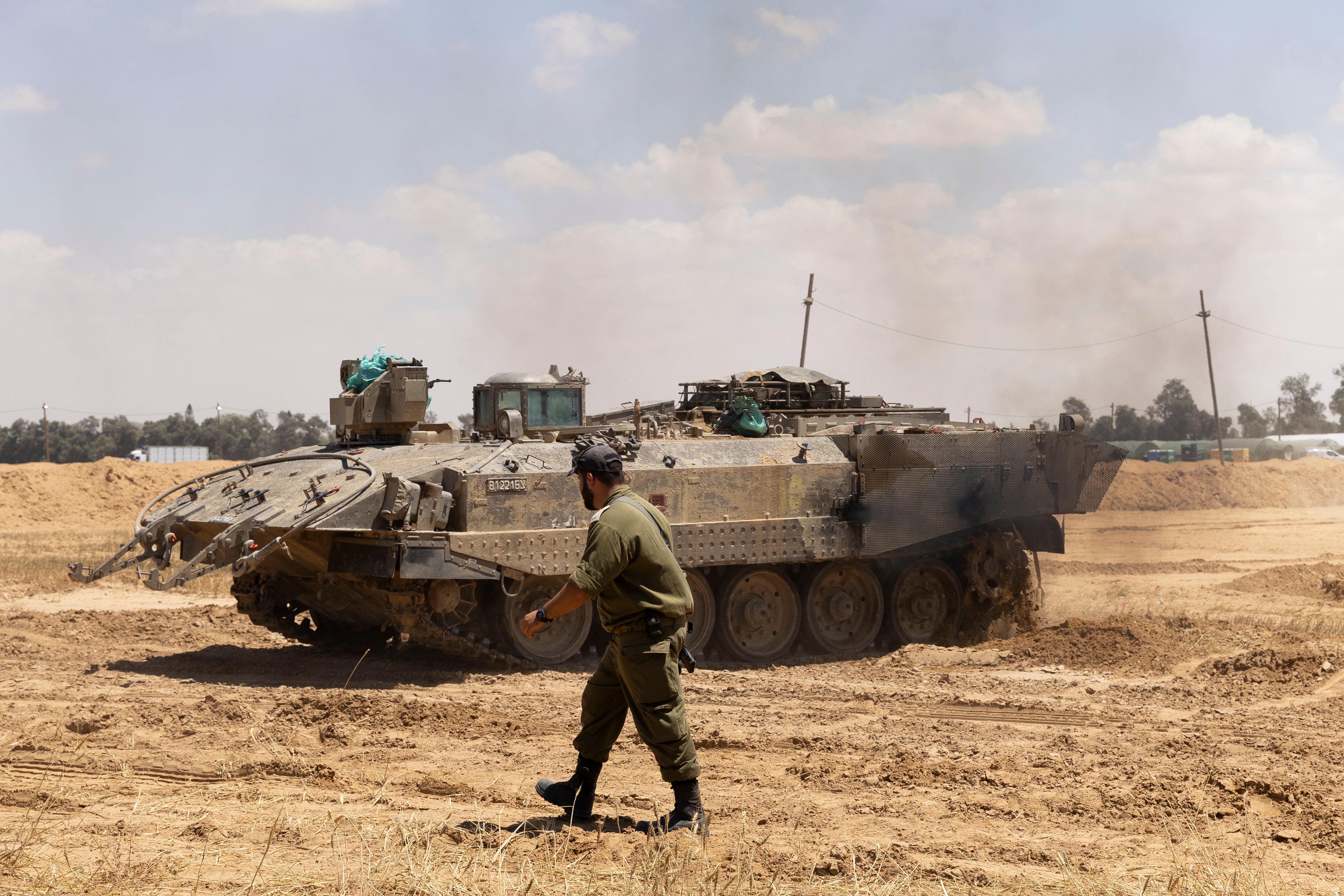 An Israeli soldier walks near an armored personnel carrier near the border with the southern Gaza Strip on 7 May 2024 in Southern Israel, Israel