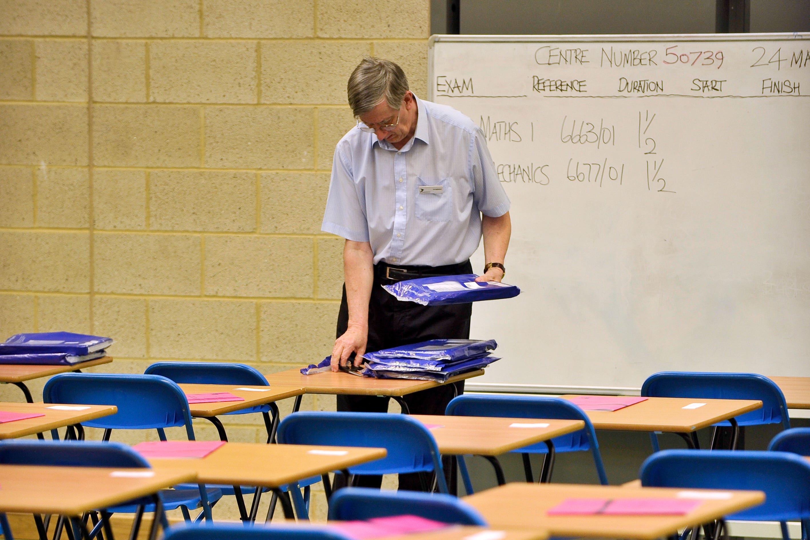 An exam invigilator prepares a maths exam inside a sports hall