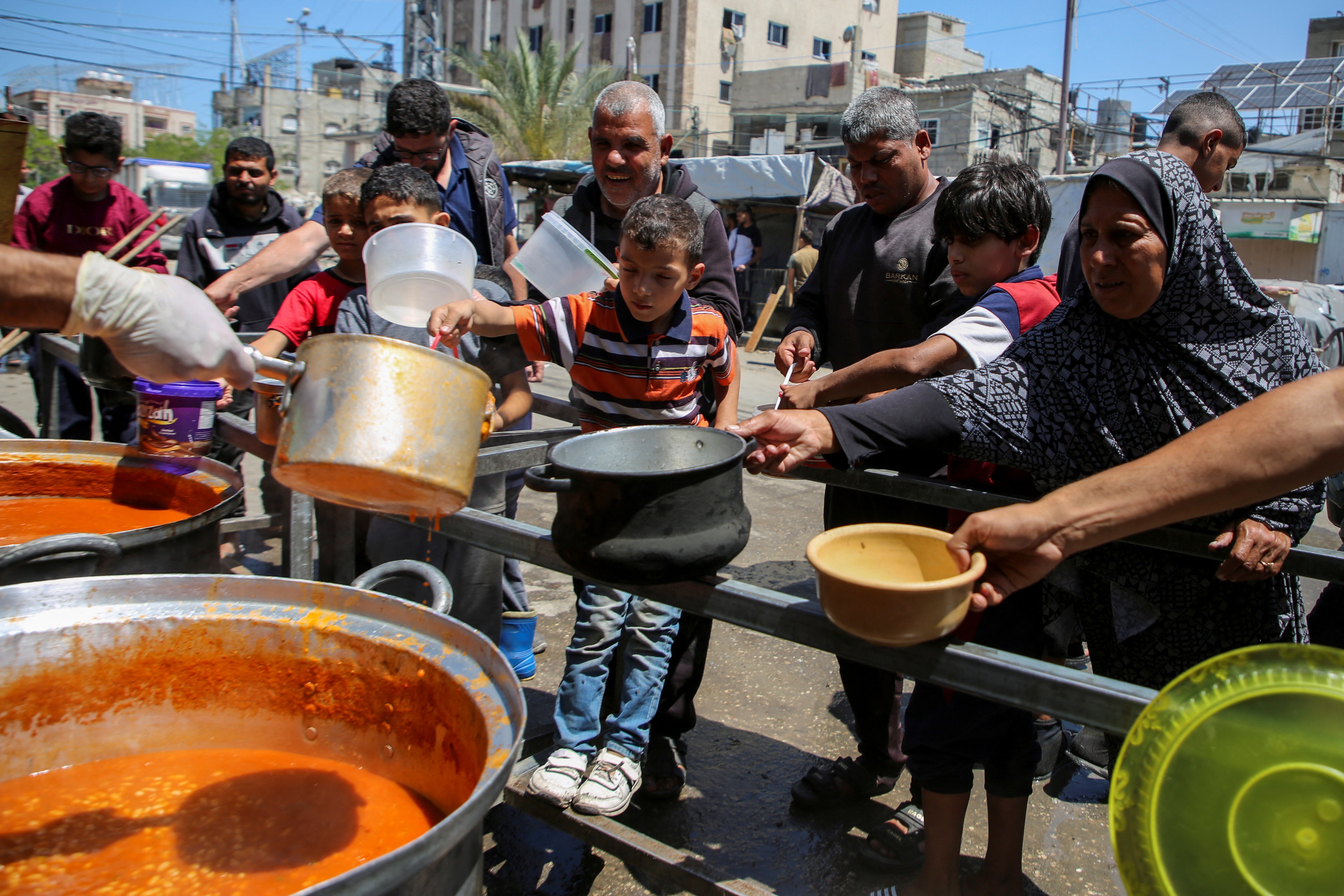 Palestinians gather to receive food cooked by a charity kitchen, amid shortages of aid supplies, after Israeli forces launched a ground and air operation in the eastern part of Rafah