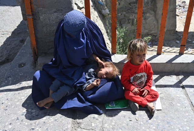 <p>A woman begs for alms in Kabul with her children </p>