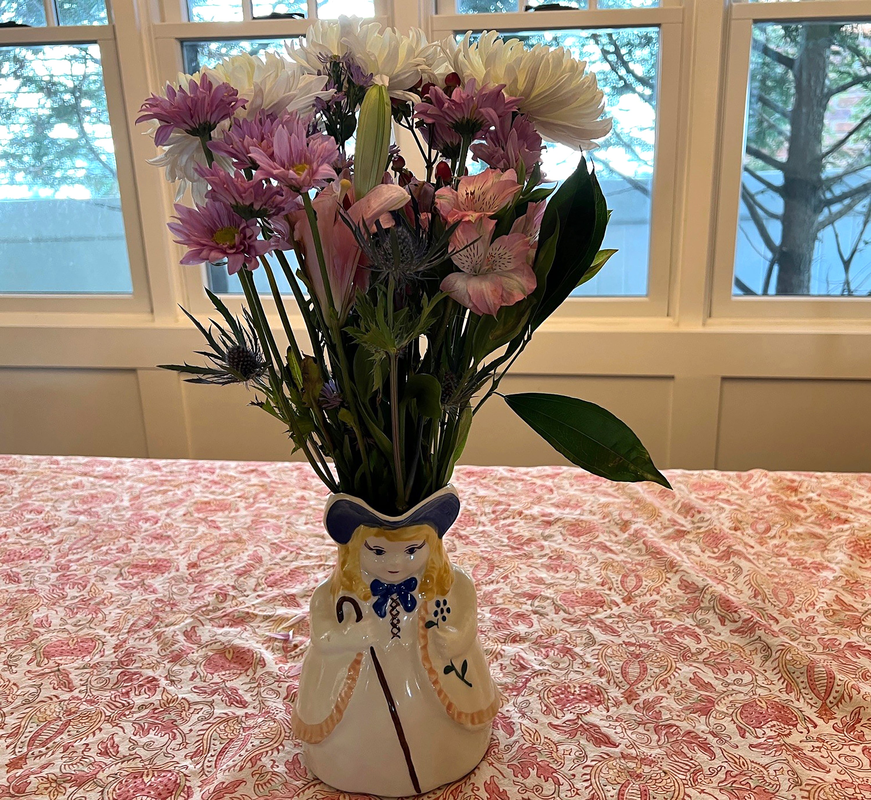 Image provided by Jessica Damiano shows a supermarket bouquet of three white chrysanthemums, a lily stem and a single rose embellished with greenery and ‘filler’ flowers