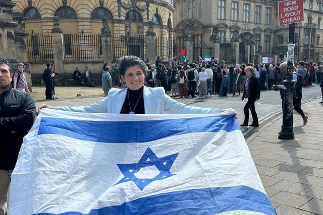 <p>Israel MP Sharren Haskel unfurls an Israeli flag at a demonstration by students of Oxford University in the city centre</p>