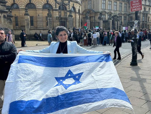<p>Israeli MP Sharren Haskel unfurls an Israeli flag at a demonstration by students of Oxford University in the city centre</p>