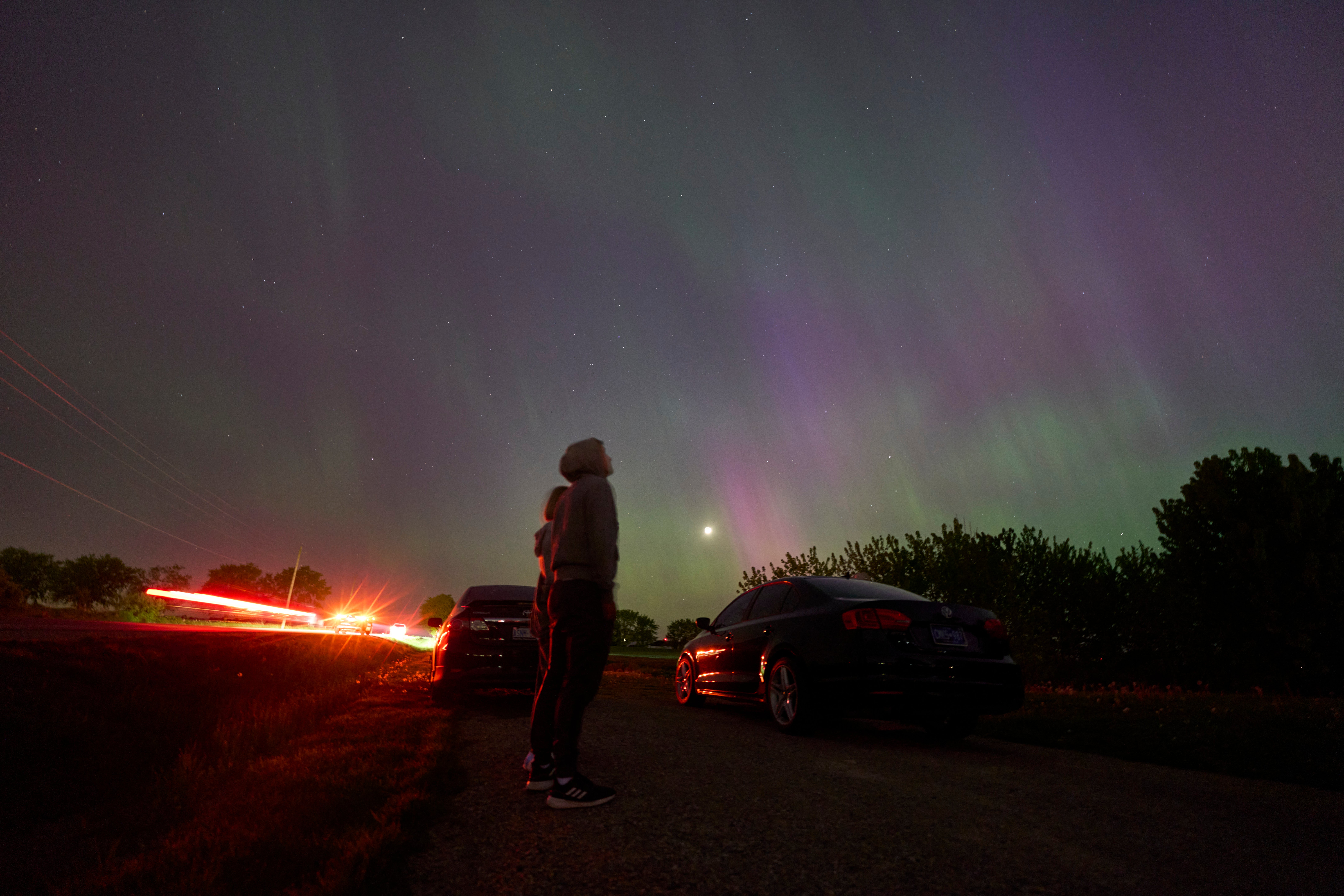 People stop along a country road near London, Ontario to watch the Northern lights or aurora borealis during a geomagnetic storm on May 10, 2024