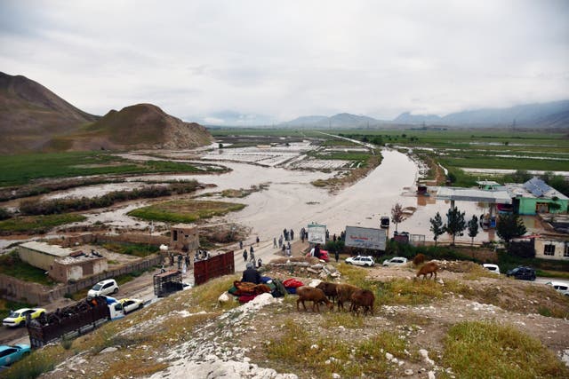 <p>Afghan people gather along a road before a floaded area between Samangan and Mazar-i-Sharif following a flash flood after a heavy rainfall in Feroz Nakhchir district of Samangan Province on 11 May 2024</p>