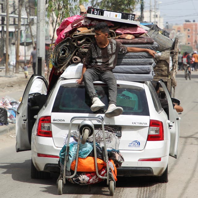 A person sits atop a vehicle loaded with belongings as they leave Rafah after Israel drops evacuation notices 