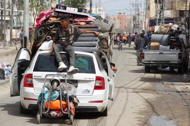 A person sits atop a vehicle loaded with belongings as they leave Rafah after Israel drops evacuation notices 