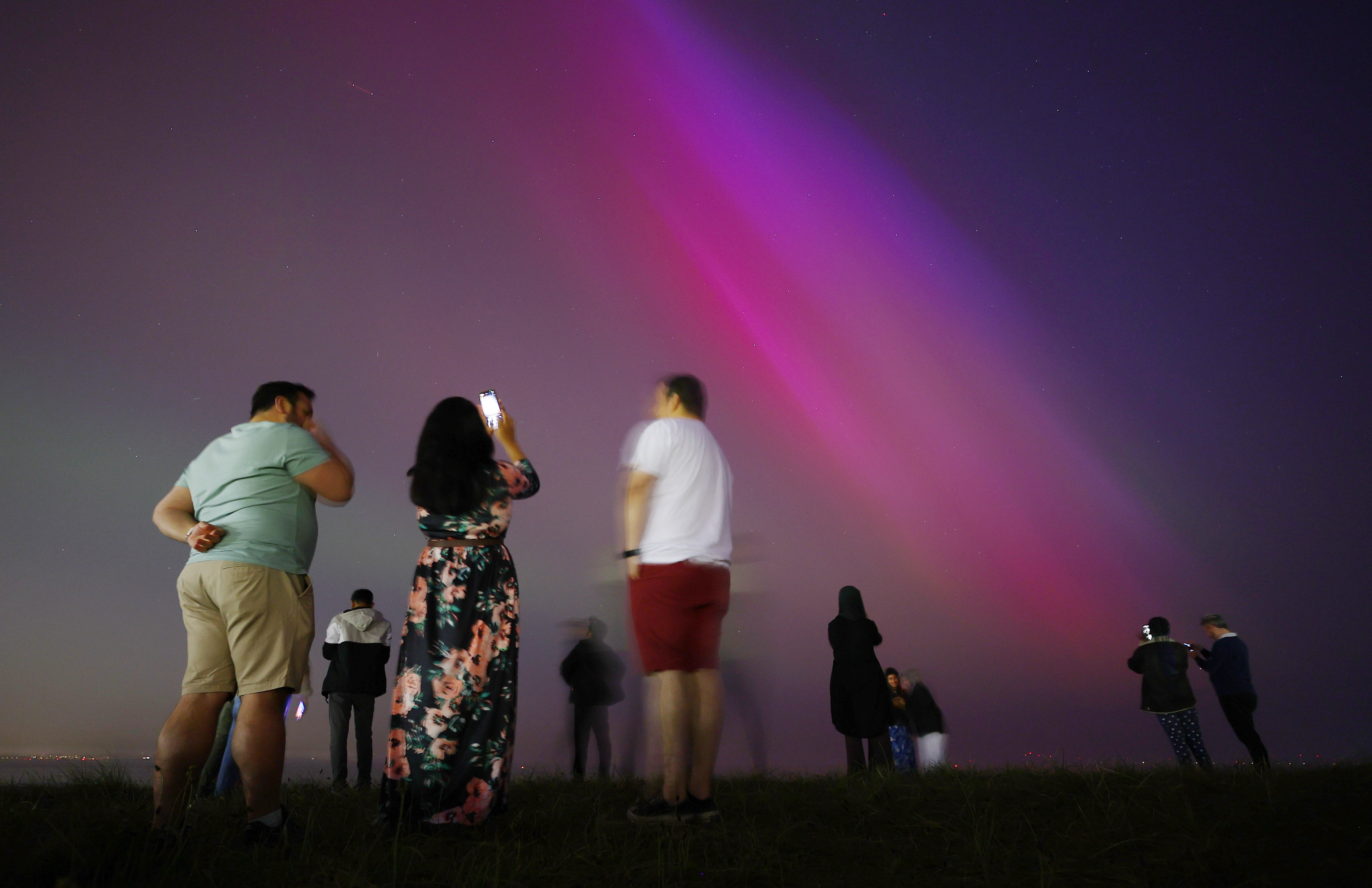 People gather at Crosby Beach to look at the Northern Lights