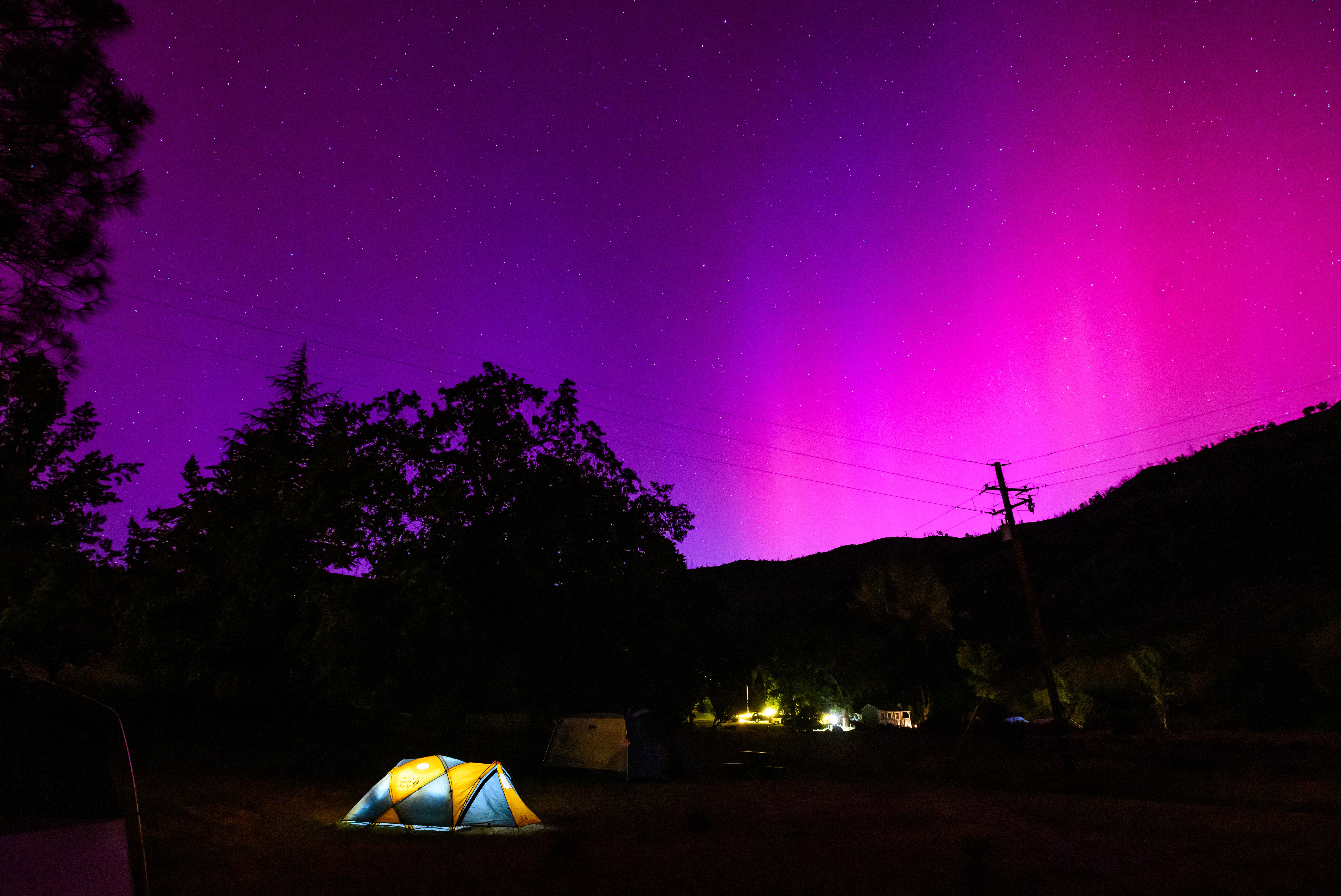Northern lights or aurora borealis illuminate the night sky over a camper’s tent north of San Francisco in Middletown, California
