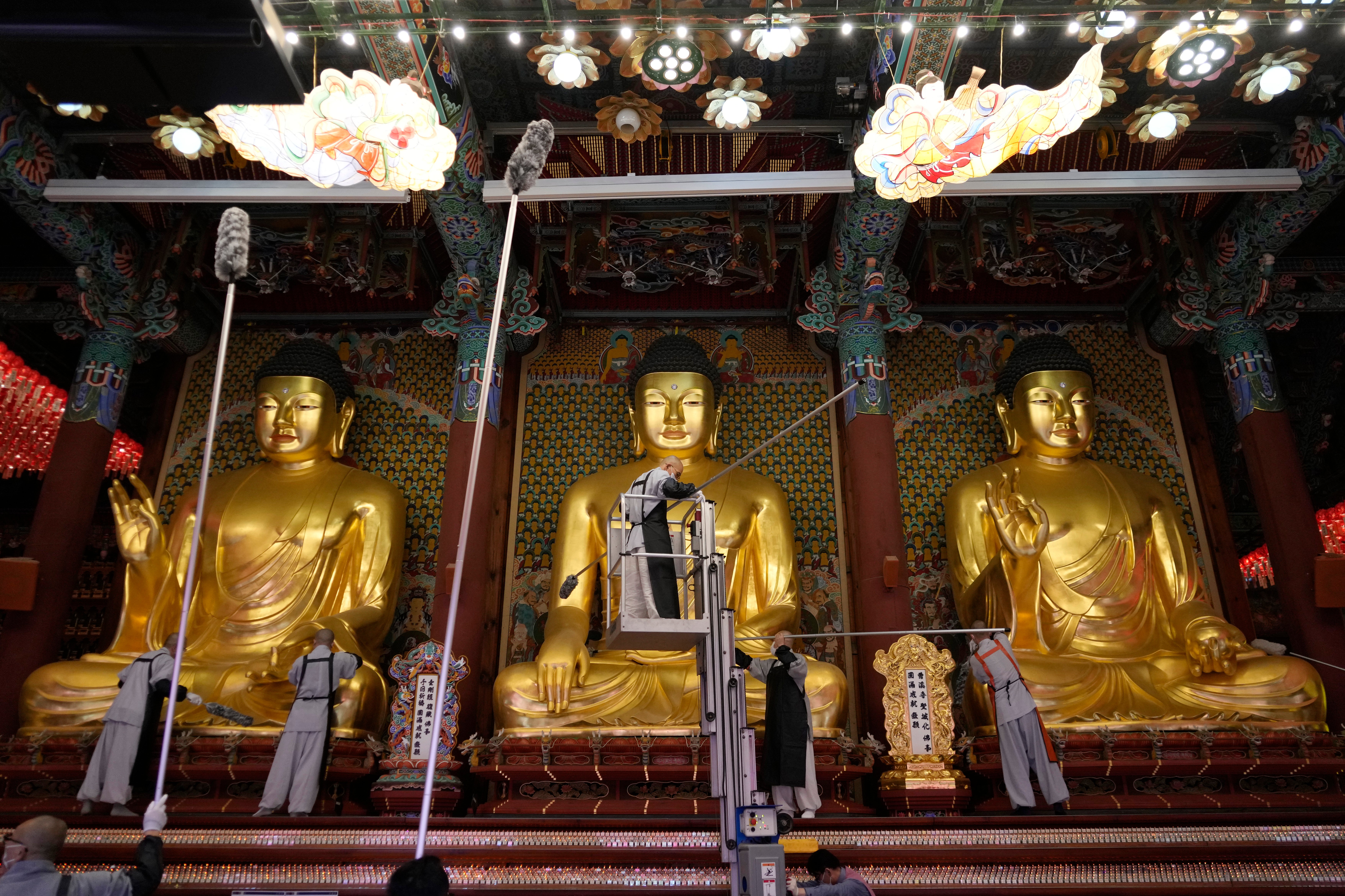 Buddhists monks clean Buddha statues ahead of the upcoming birthday of Buddha on May 15, at the Jogye temple in Seoul