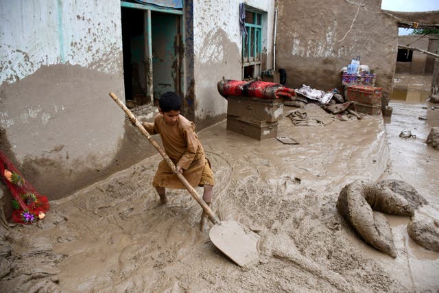<p>An Afghan boy shovels mud from the courtyard of a house following flash floods after heavy rainfall at a village in Baghlan-e-Markazi district of Baghlan province on 11 May 2024</p>