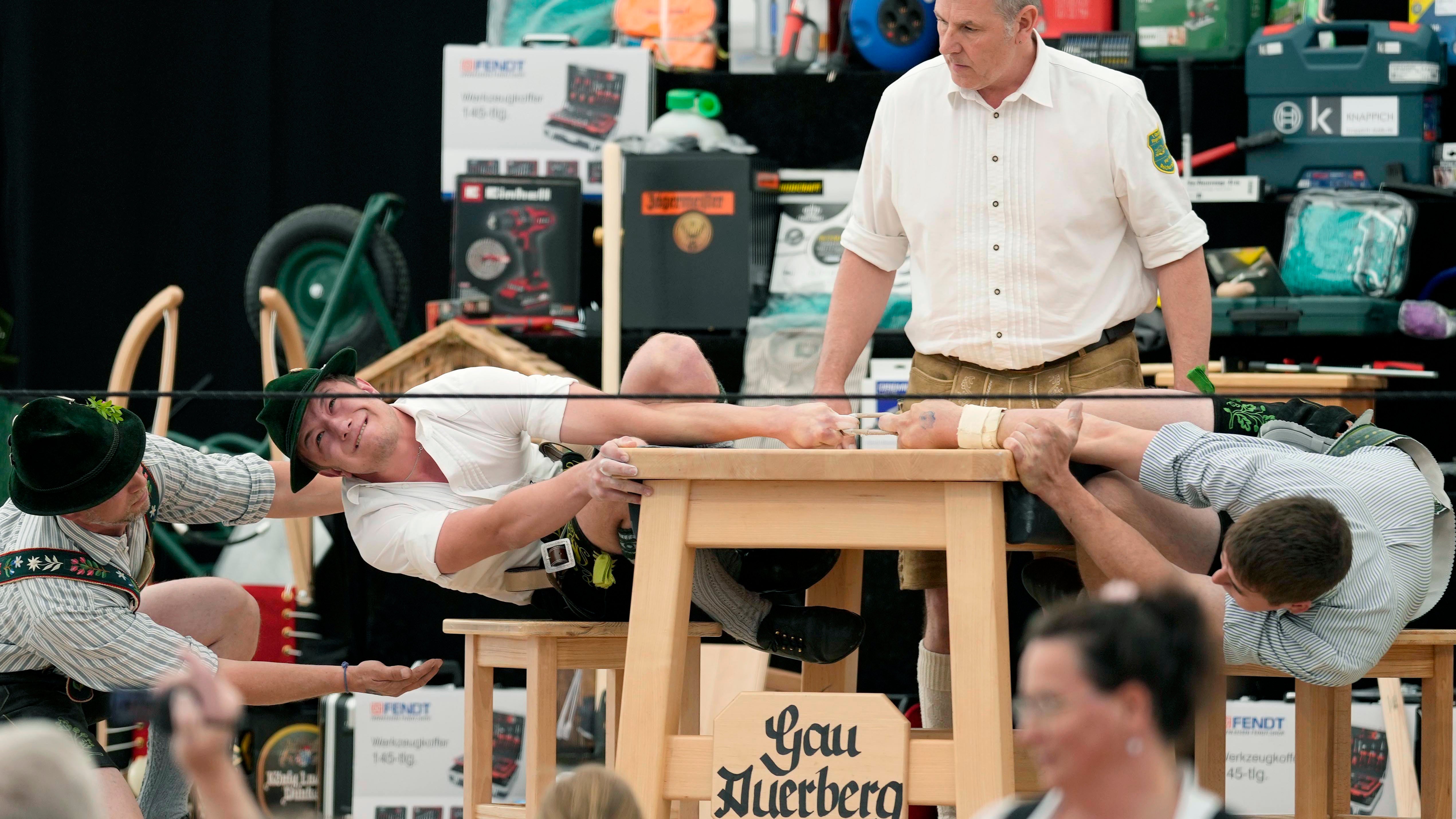 A man dressed in traditional clothes tries to pull his opponent over the table at the German Championships
