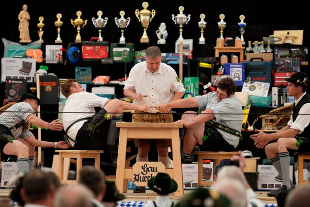 <p>Germany Finger A referee monitors the leather ring held by two competitors with their middle fingers at the German finger strength Championships </p>