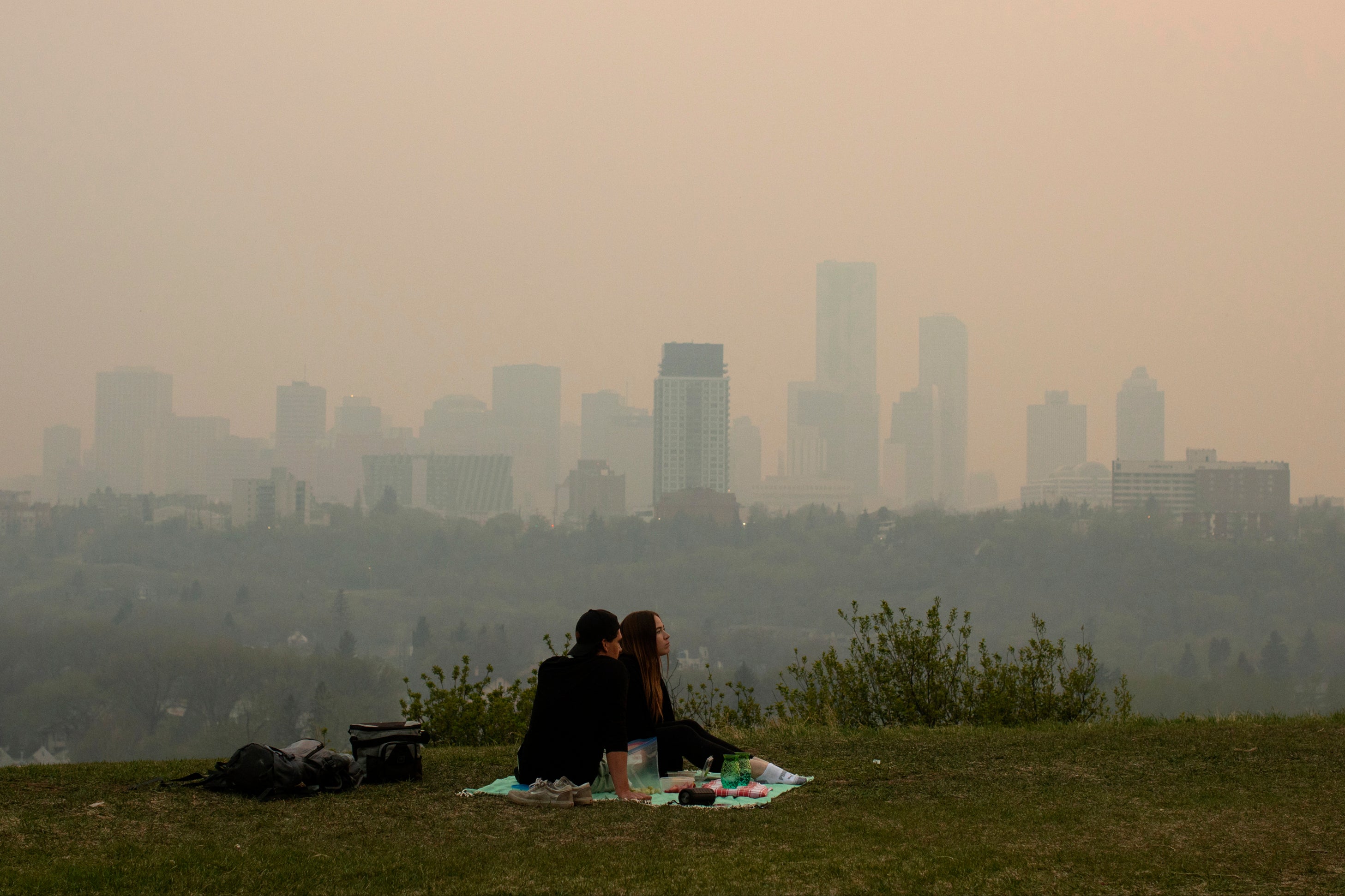 Smoke from wildfires blankets the city as a couple has a picnic in Edmonton, Alberta on May 11, 2024