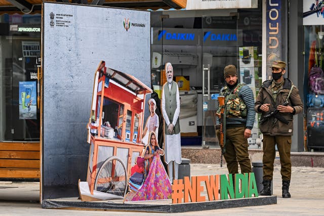 <p>Security personnel stand guard next to a cut-out portrait of India’s PM Narendra Modi in central Srinagar</p>
