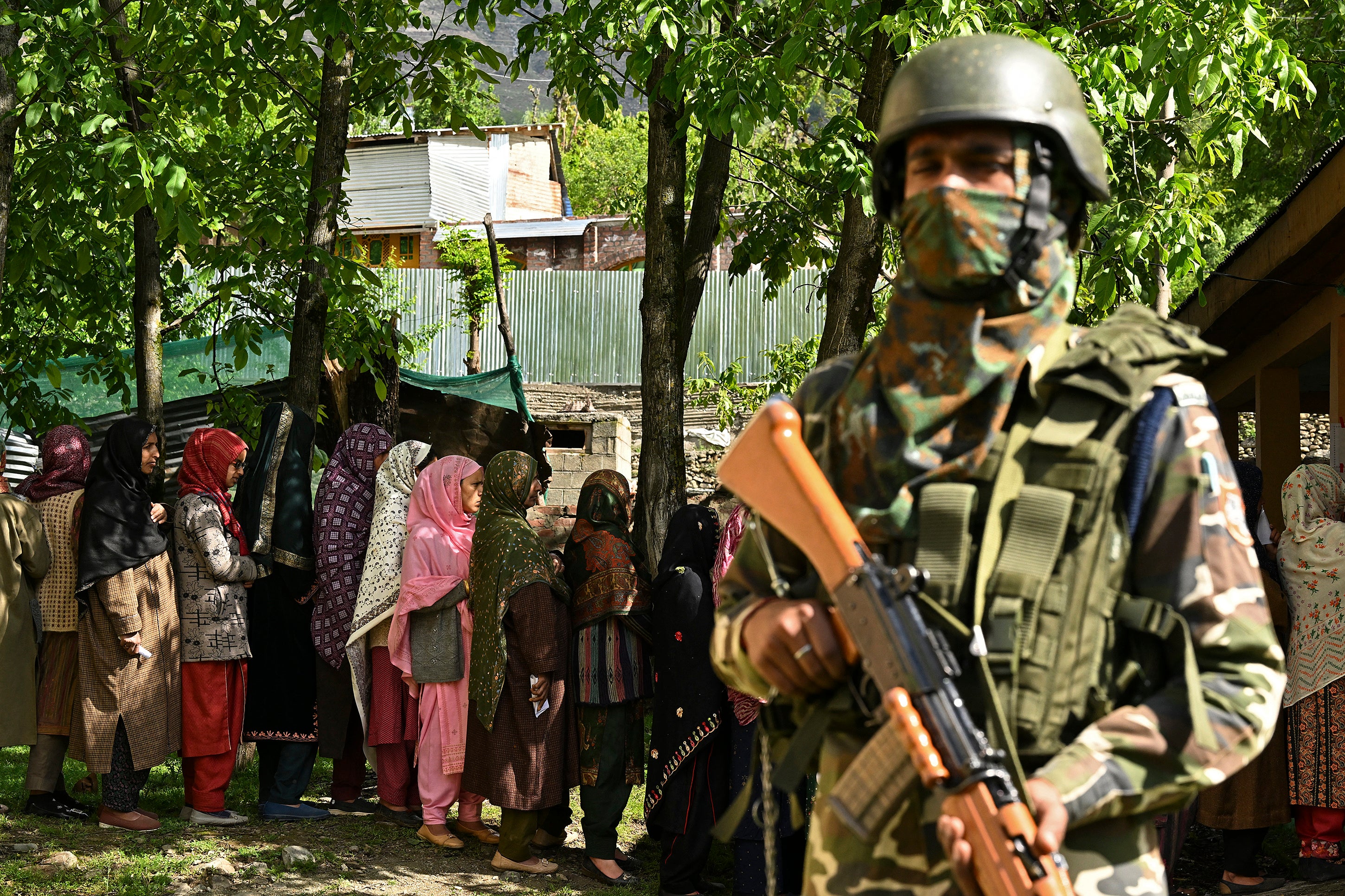 An Indian security personnel stands guard as voters queue up to cast their ballots at a polling station in Ganderbal district, northeast of Srinagar