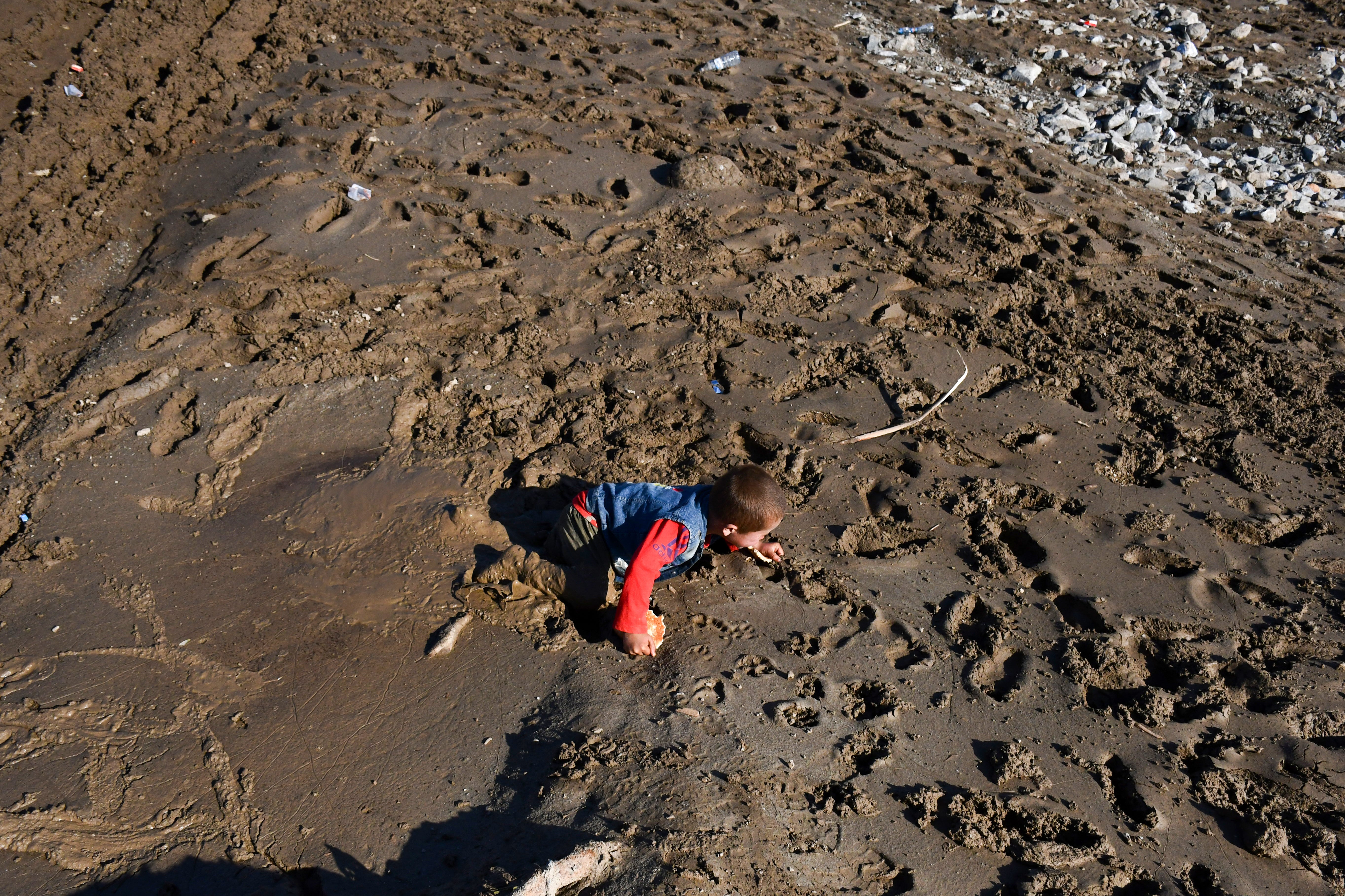 An Afghan child crawls in the mud after floods in the Burka district of Baghlan province