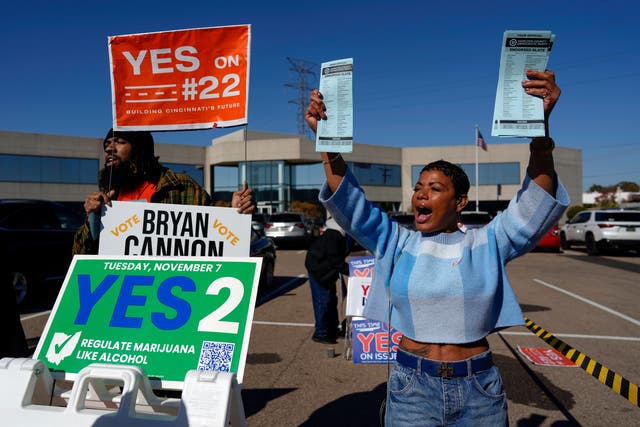 <p>Nikko Griffin, left, and Tyra Patterson, call out to arriving voters for several issues, including Issue 2, legalizing recreational marijuana, at a parking lot during early in-person voting in Cincinnati, Nov. 2, 2023</p>