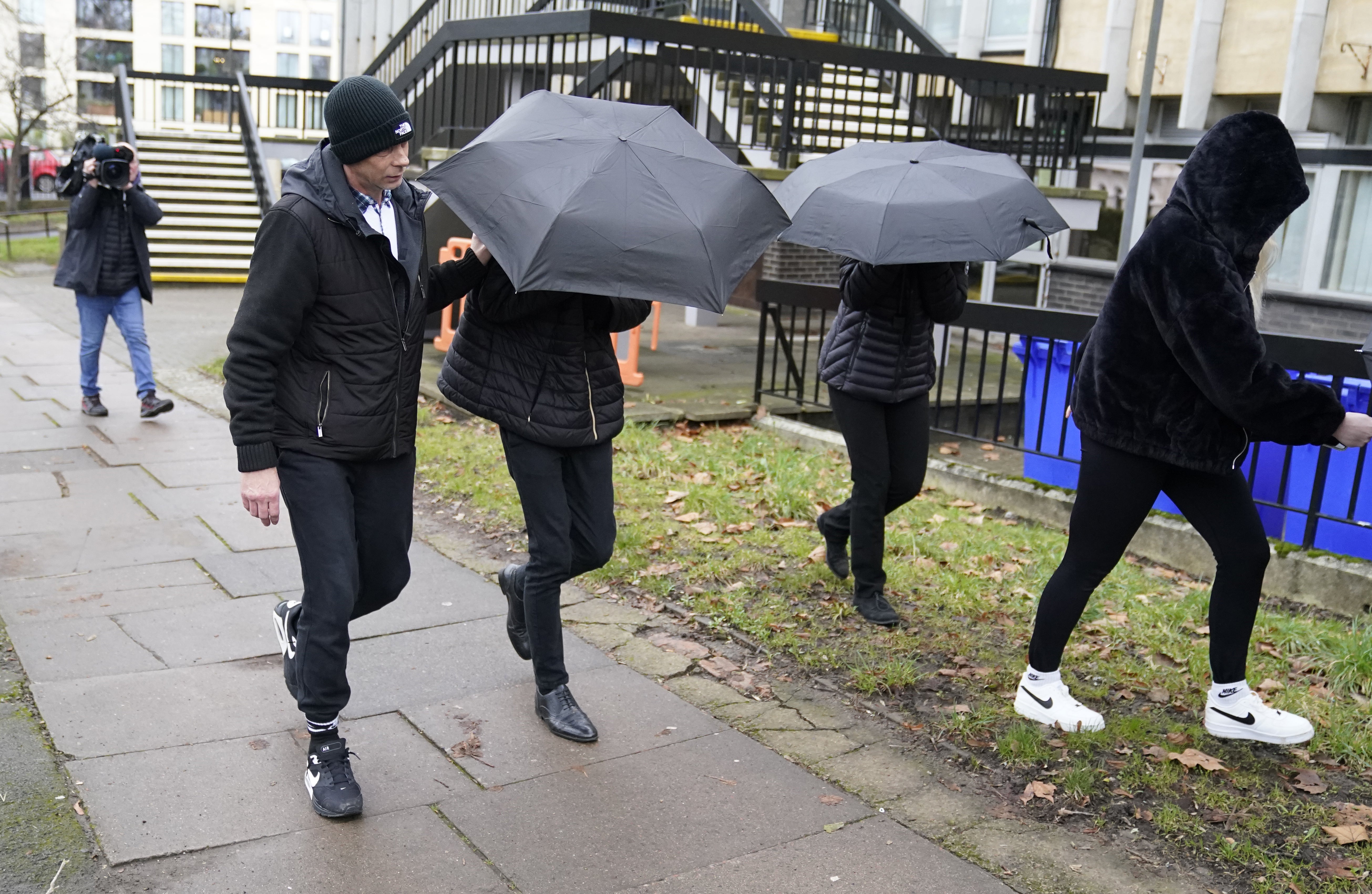 Elliot Benham, 25, (second left under umbrella) and Sophie Harvey, 25, (second right under umbrella), at an earlier hearing at Cheltenham Magistrates’ Court