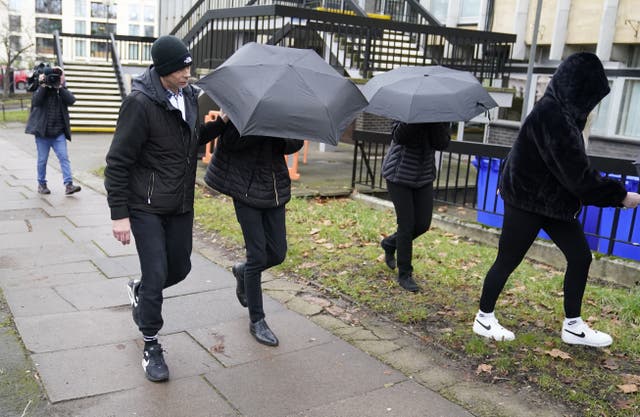 <p>Elliot Benham, 25, (second left under umbrella) and Sophie Harvey, 25, (second right under umbrella), at an earlier hearing at Cheltenham Magistrates’ Court </p>