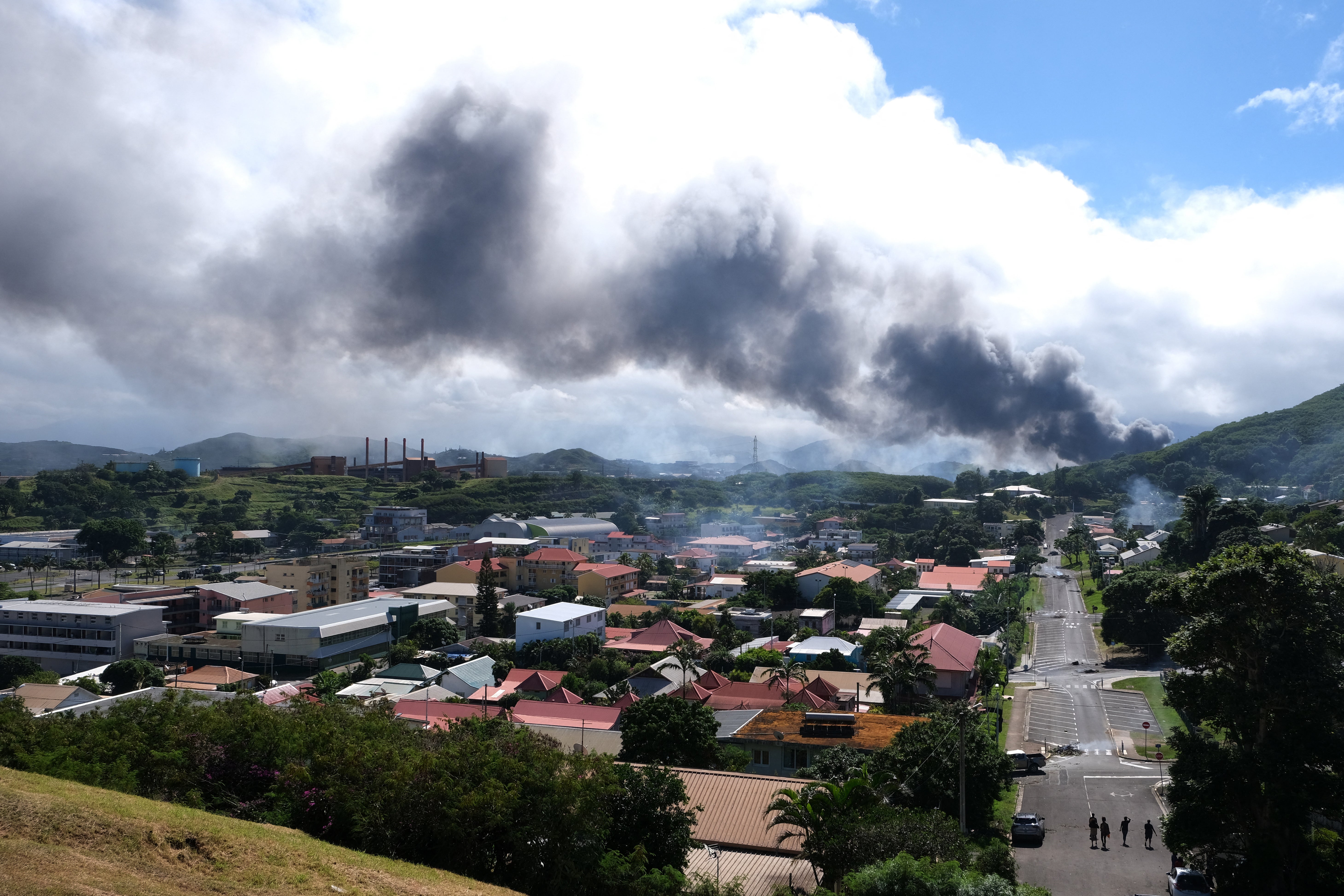 This picture taken on May 14, 2024, shows smoke rising in the distance amid protests linked to a debate on a constitutional bill aimed at enlarging the electorate for upcoming elections of the overseas French territory of New Caledonia.