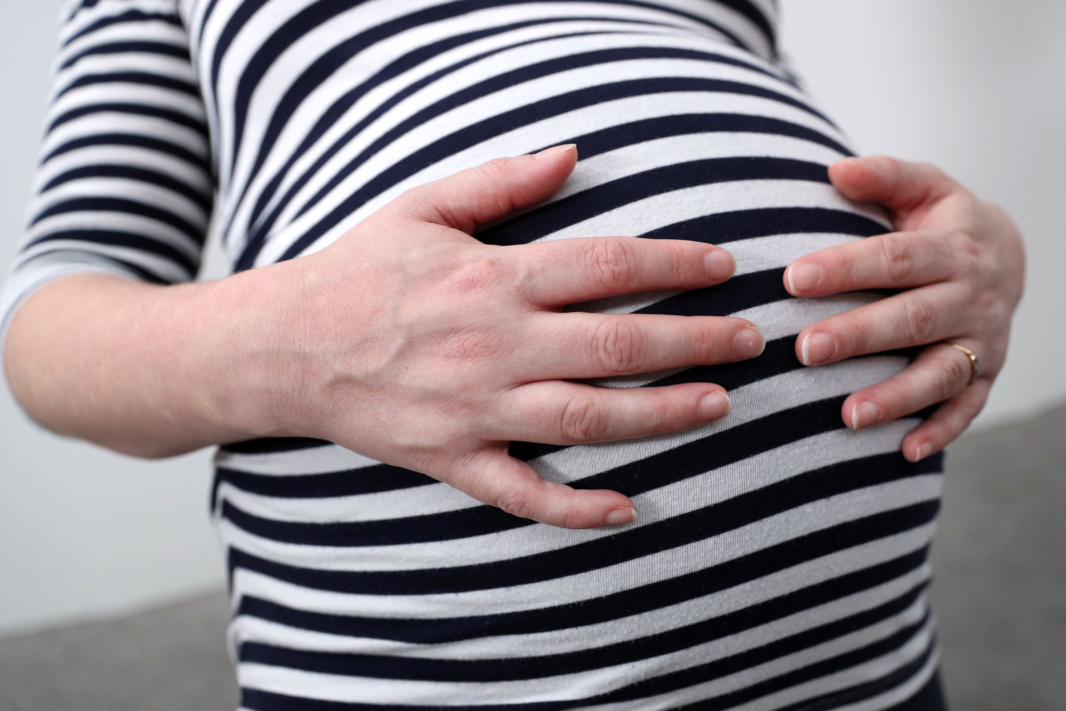 A pregnant woman holds her stomach (Andrew Matthews/PA)