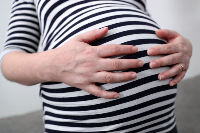 A pregnant woman holds her stomach (Andrew Matthews/PA)