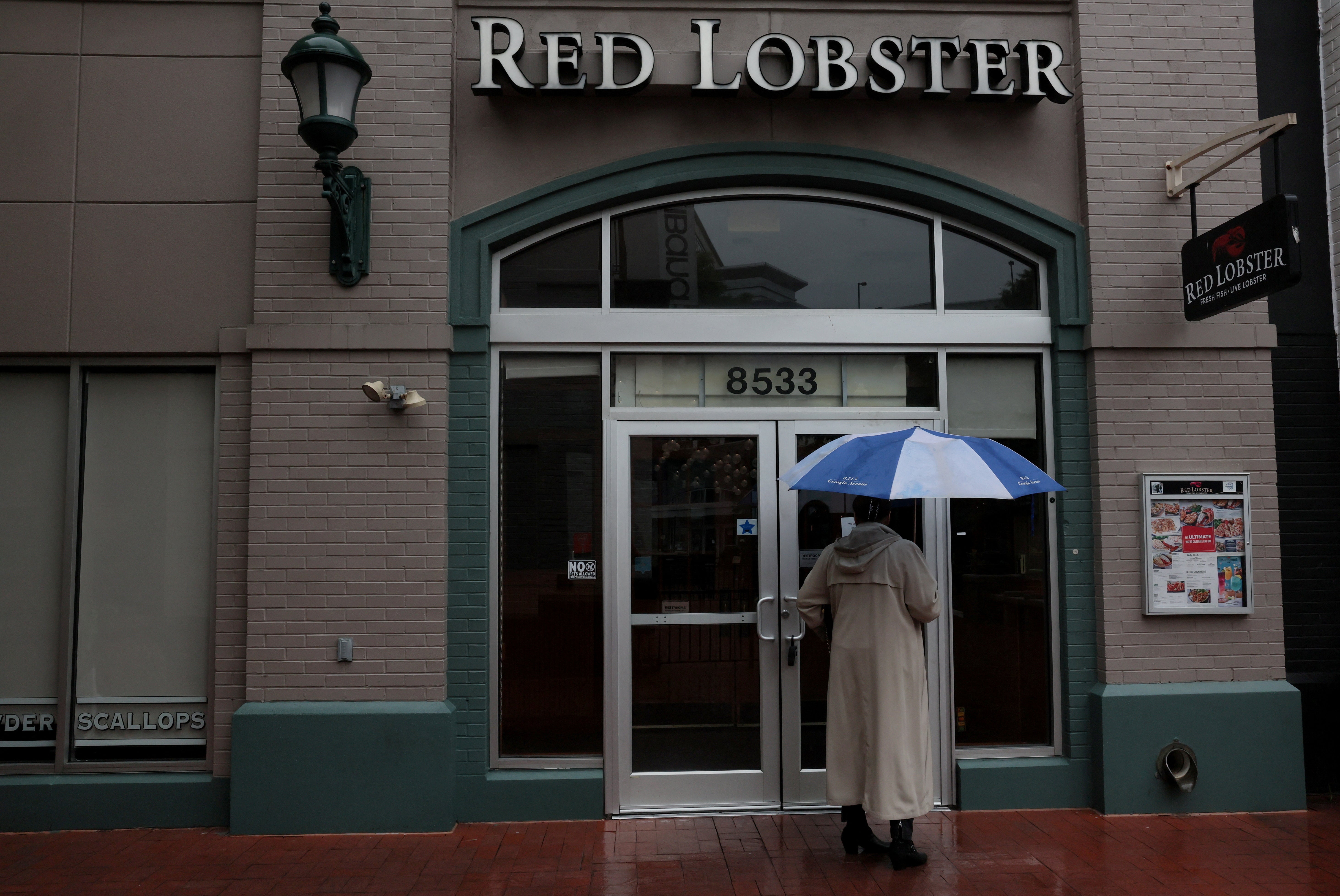 A person reads a sign taped to a door announcing the closure of a Red Lobster in Silver Spring, Maryland