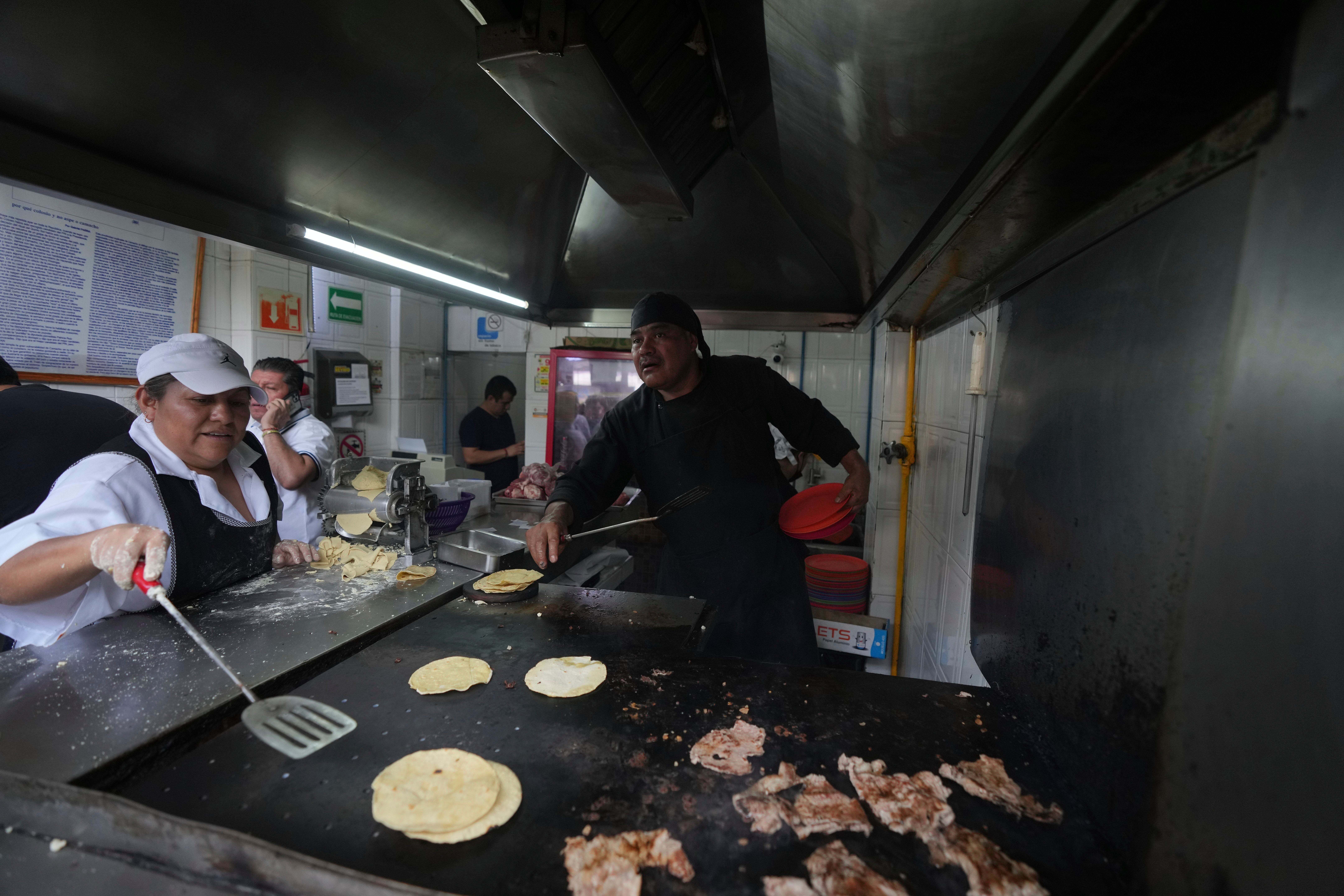 A worker warms corn tortillas on a griddle at the Tacos El Califa de León taco stand, in Mexico City