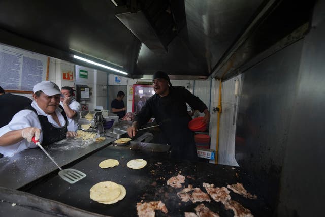 <p>A worker warms corn tortillas on a griddle at the Tacos El Califa de León taco stand, in Mexico City</p>