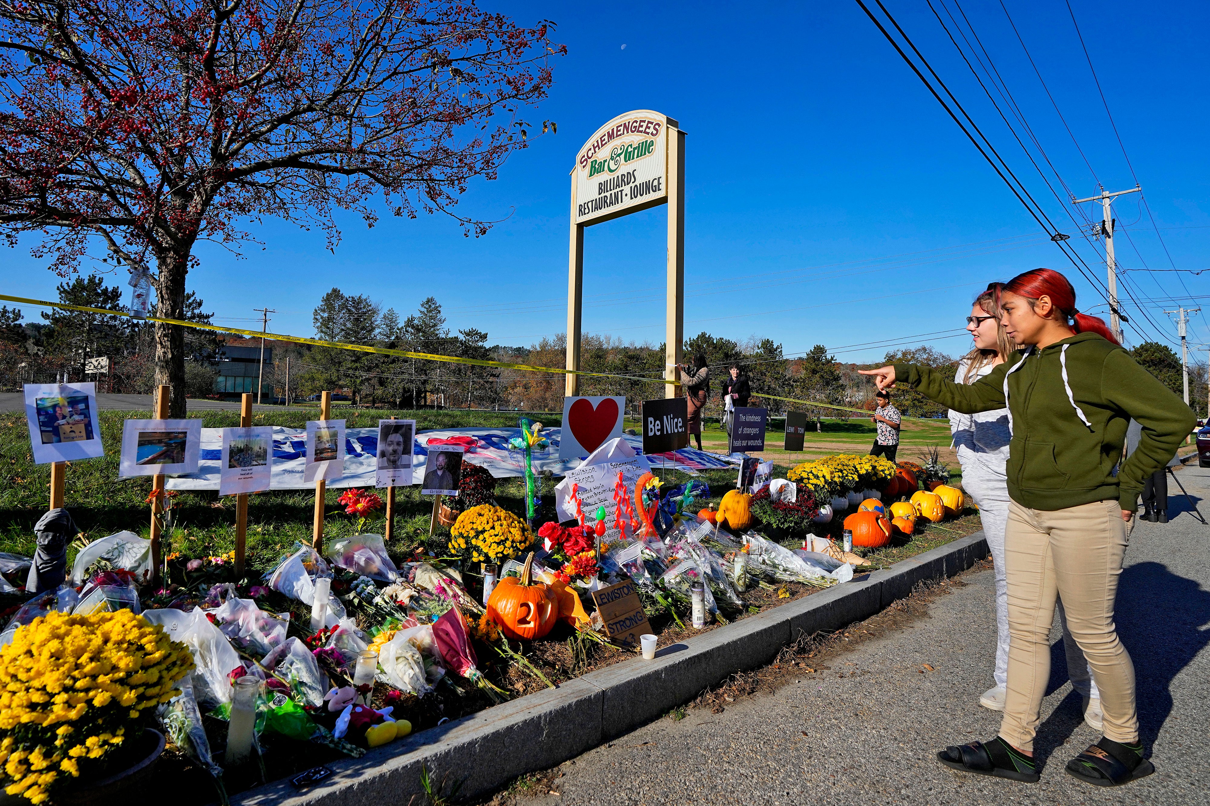Community members look at a memorial outside Schemengees Bar & Grille about one week after a mass shooting in Lewiston, Maine