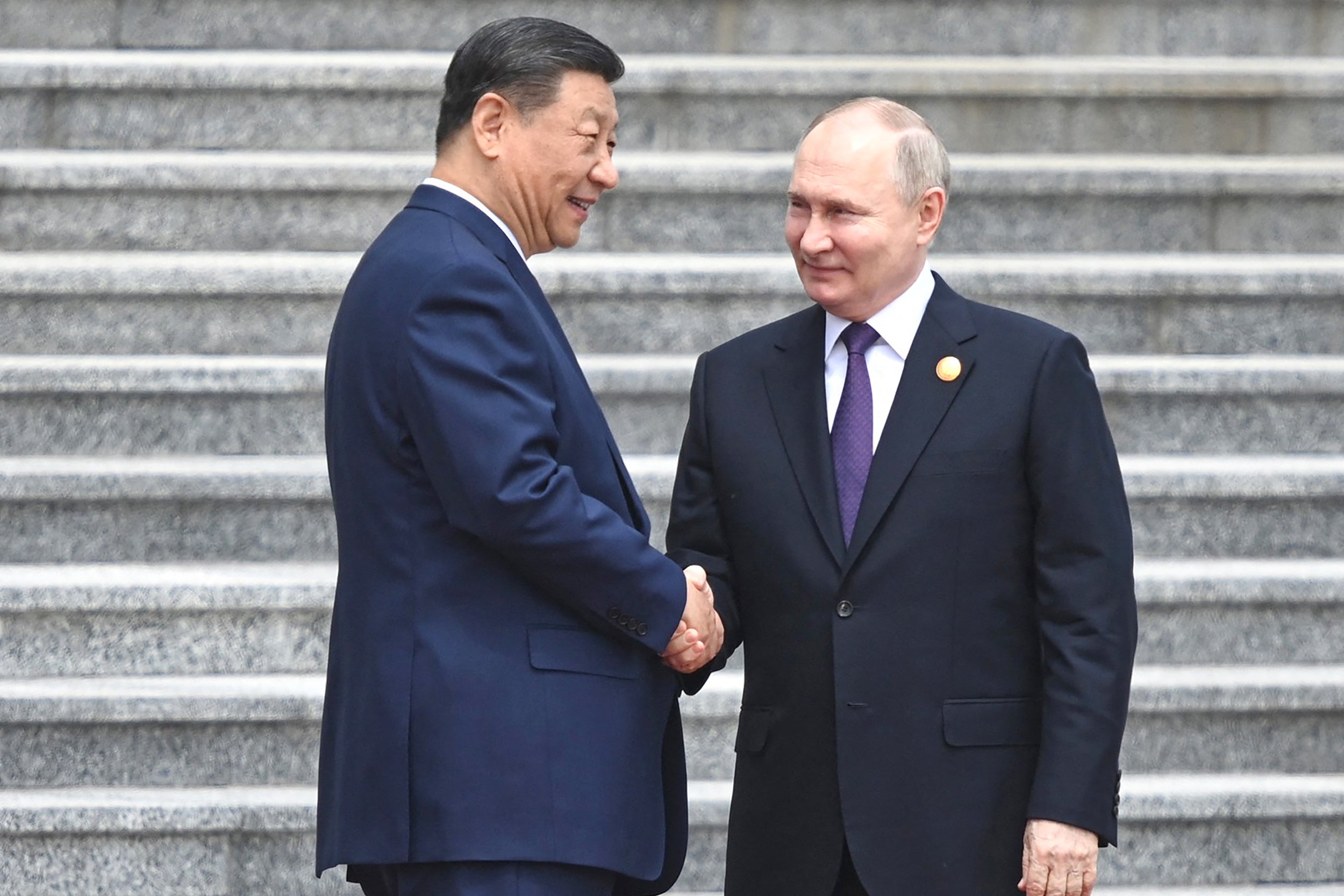 Vladimir Putin (R) and China's President Xi Jinping shake hands during an official welcoming ceremony in front of the Great Hall of the People in Tiananmen Square in Beijing