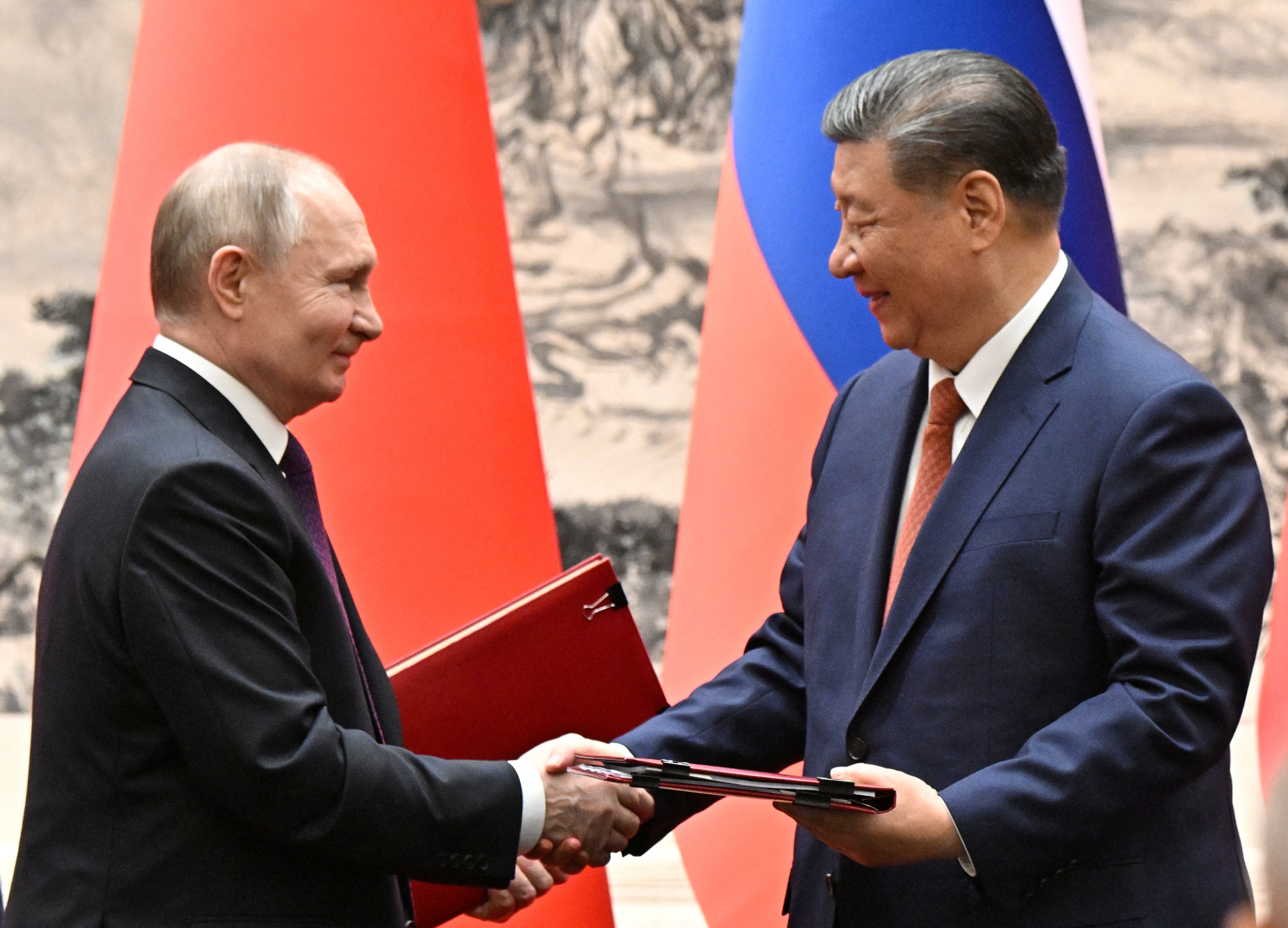 Russian President Vladimir Putin and Chinese President Xi Jinping exchange bilateral documents during a meeting in Beijing