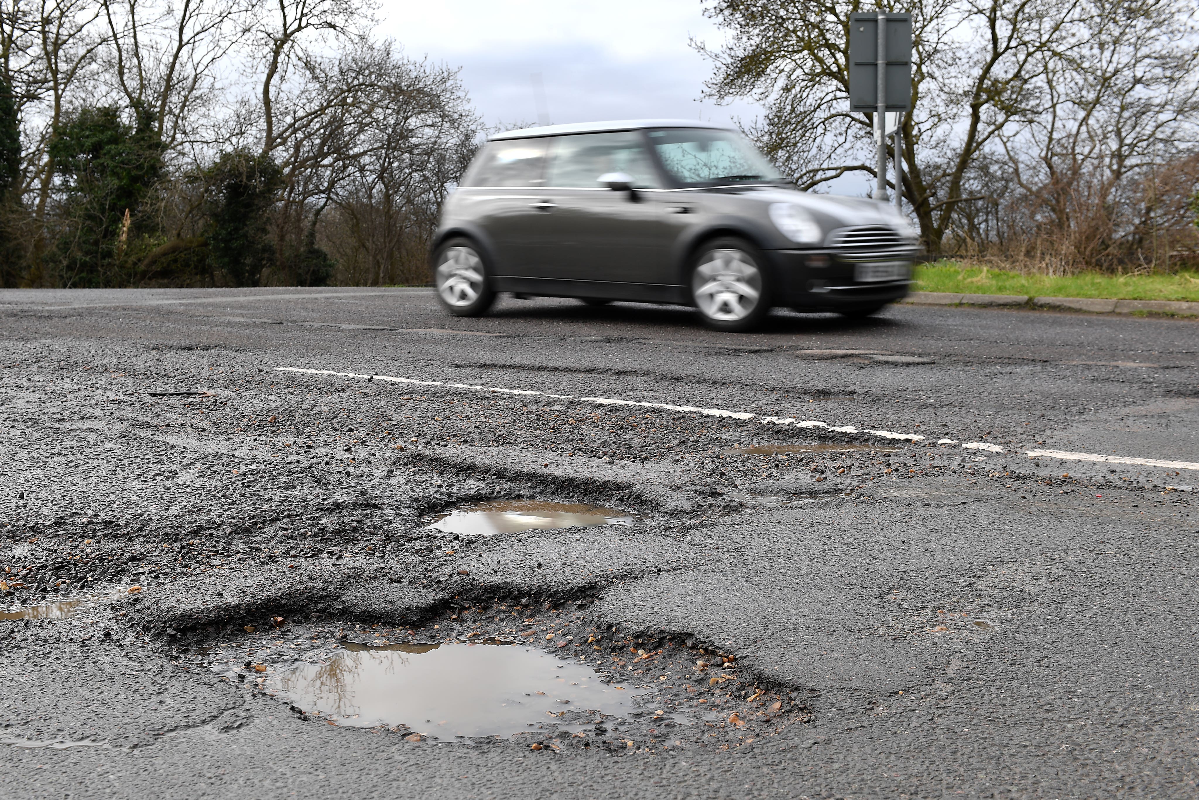 A car passes potholes in a road near Peterborough