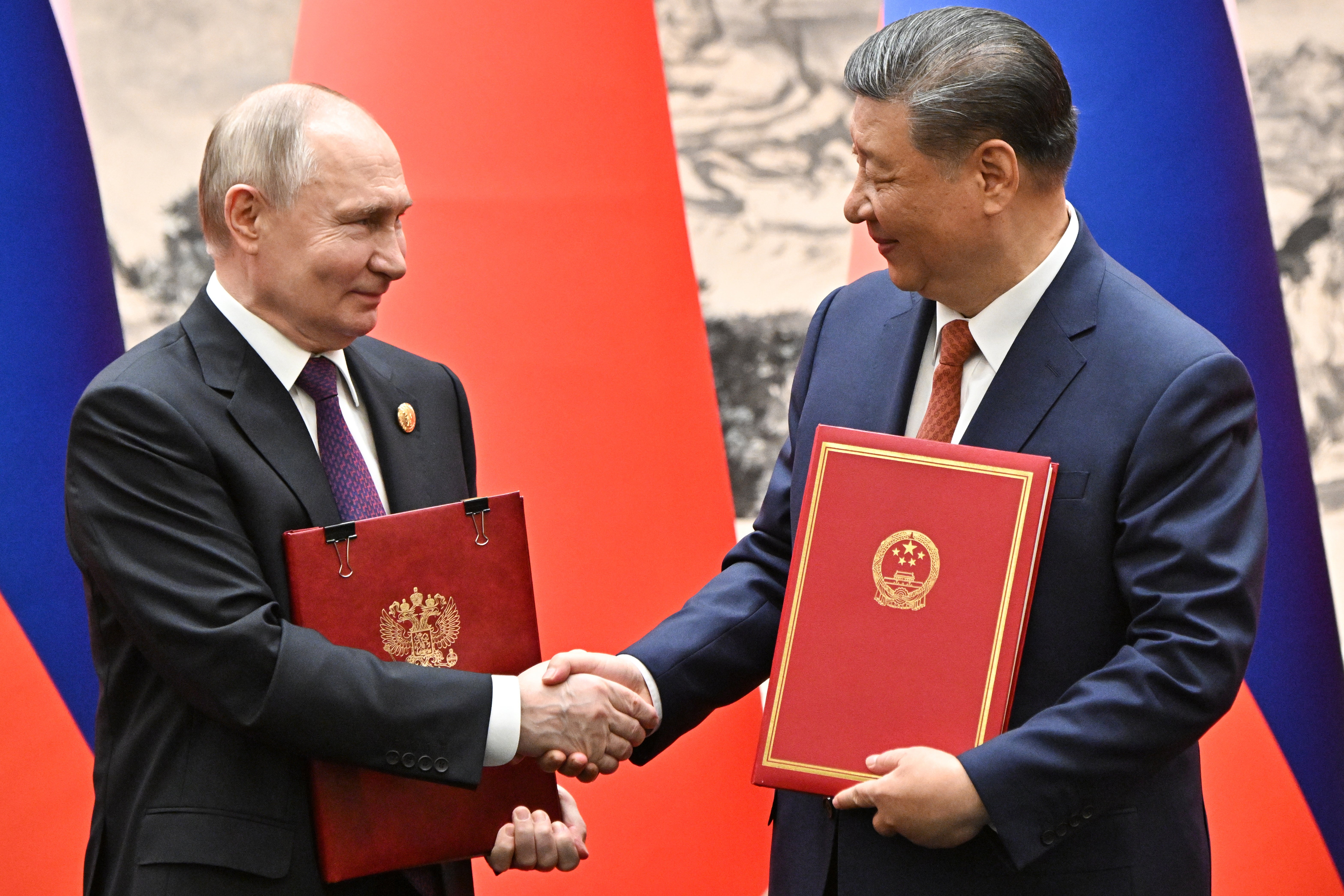Russian President Vladimir Putin (L) and Chinese President Xi Jinping shake hands as they attend a signing ceremony following a meeting in expanded format at the Great Hall of the People