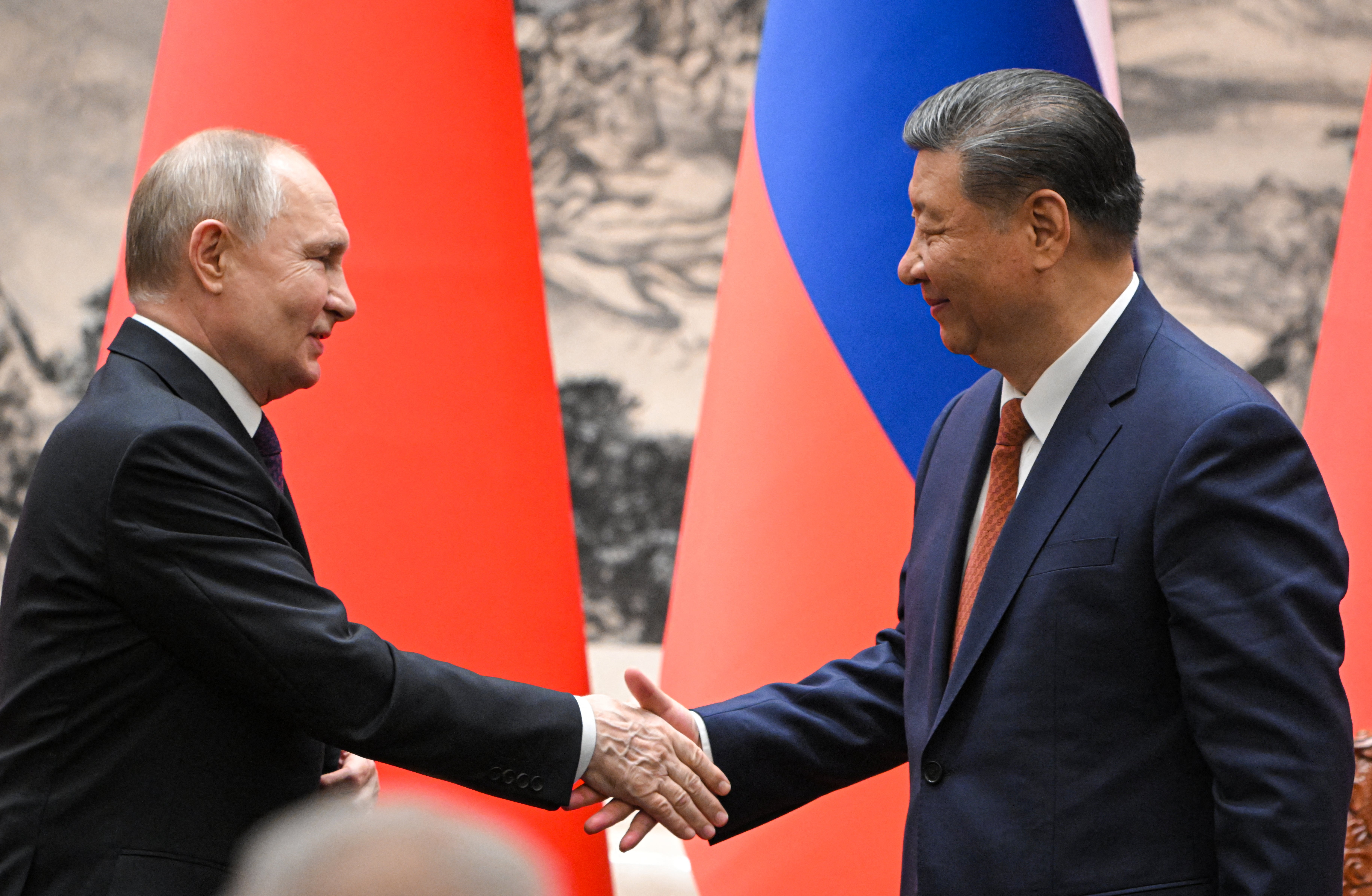 Vladimir Putin and Xi Jinping shake hands for the cameras following their talks in Beijing on Thursday