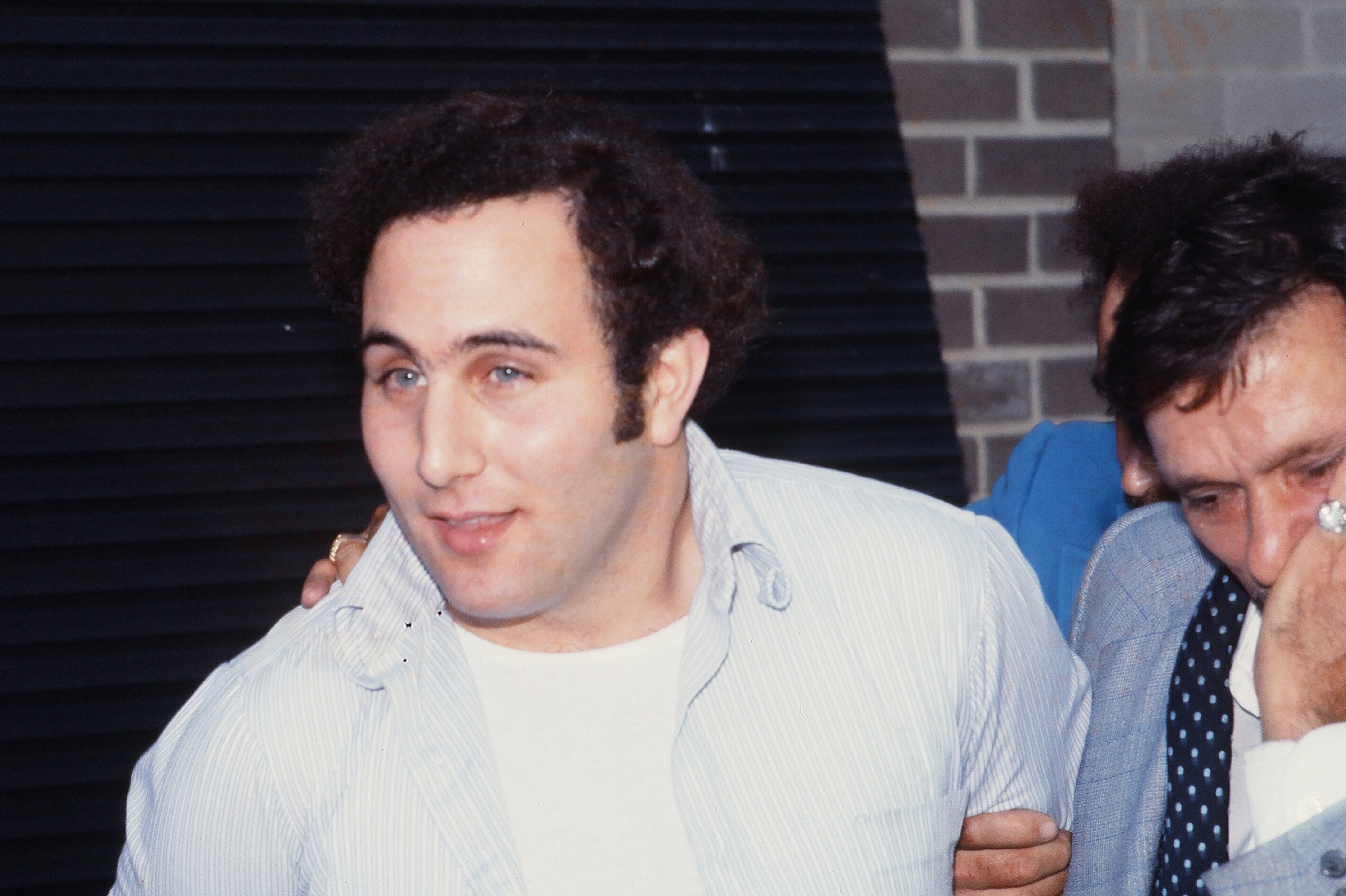 Police officers escort serial killer David Berkowitz, known as the Son of Sam, into the 84th precinct station on August 10, 1977.