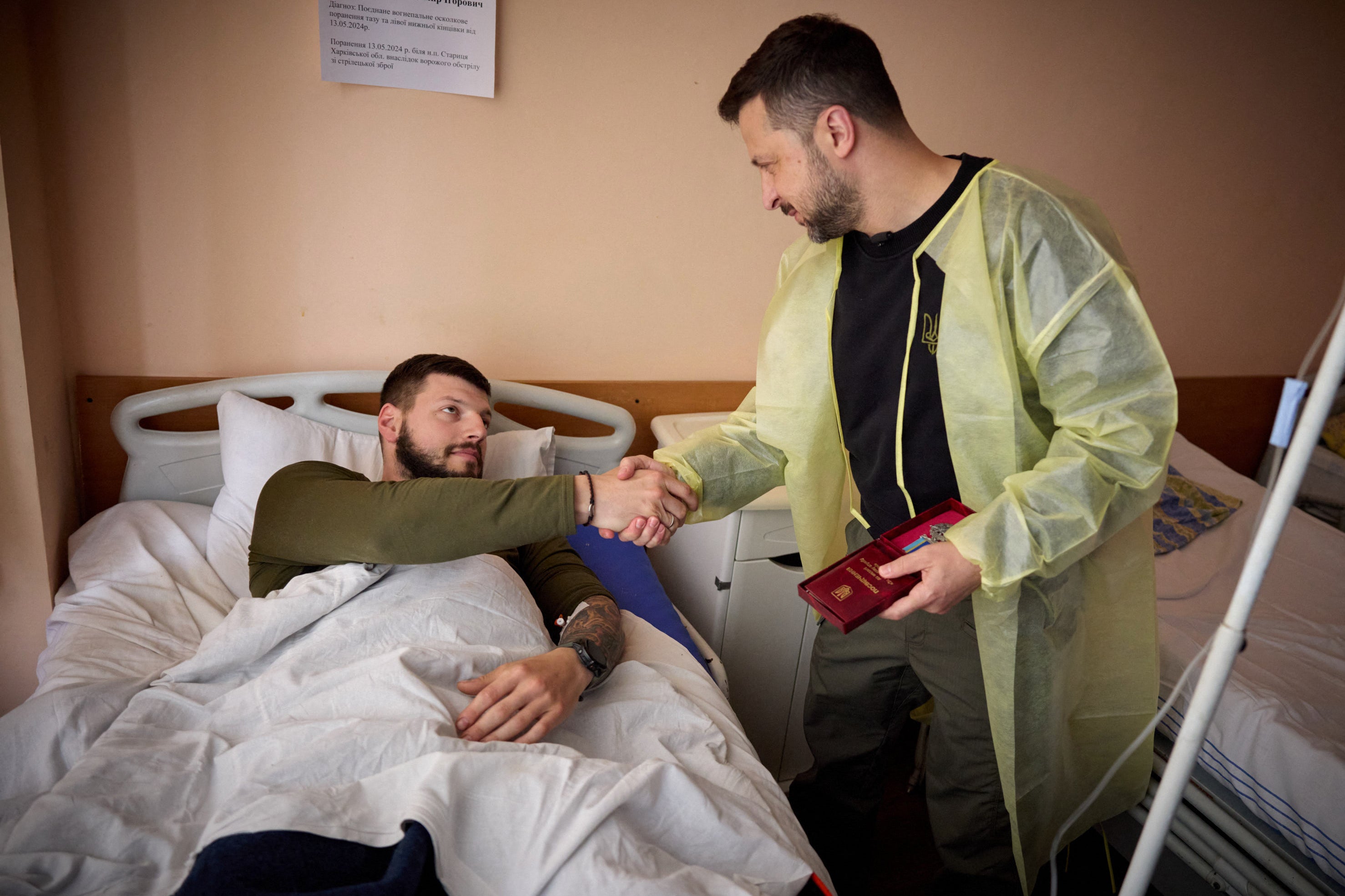 Ukraine’s President Volodymyr Zelensky (R) awards a wounded Ukrainian serviceman at a hospital in Kharkiv