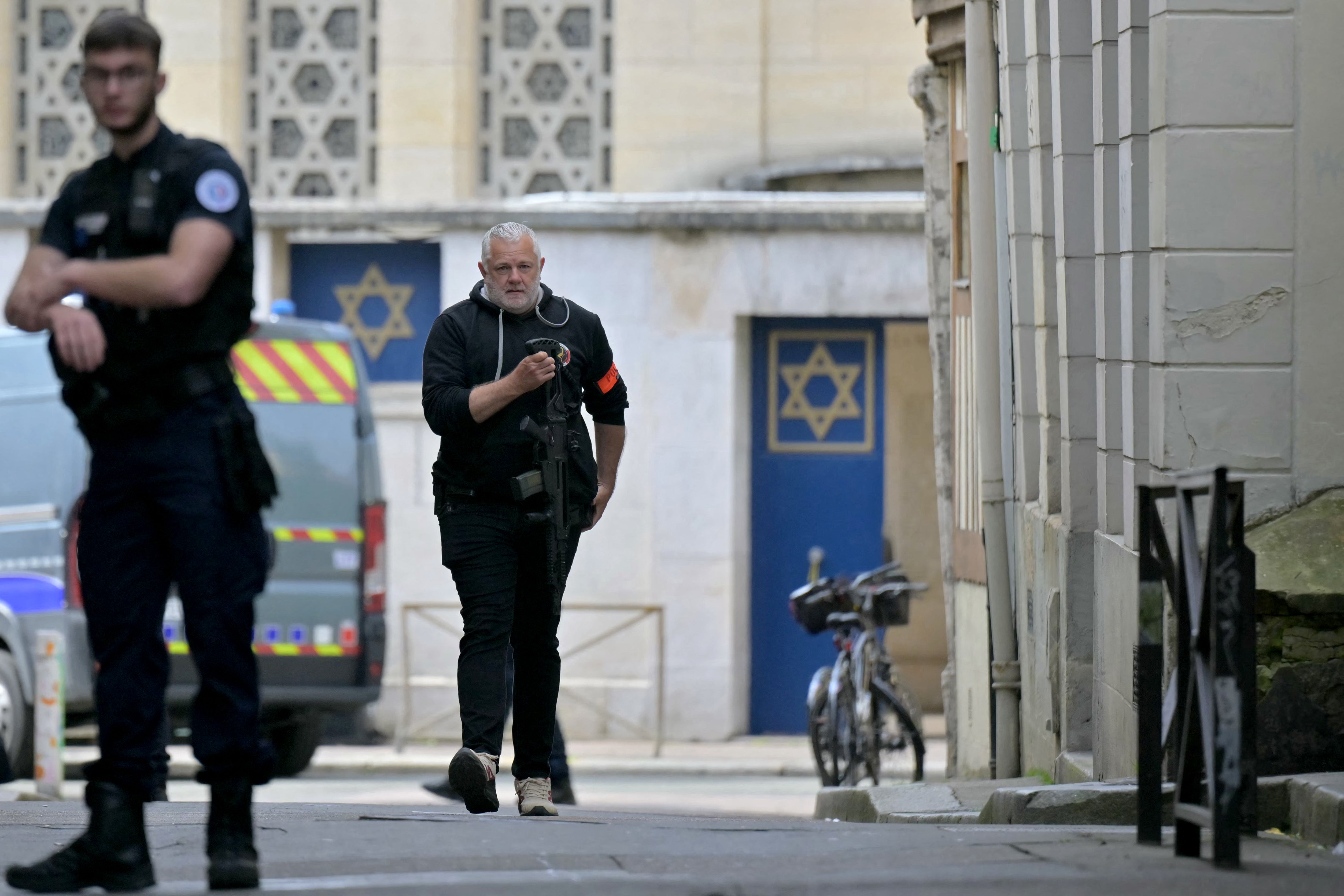 A police officer holds a riffle as he walks by an entrance of a synagogue in the Normandy city of Rouen where French police have killed earlier an armed man who was trying to set fire to the building