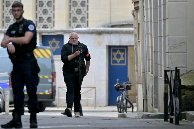 <p>A police officer holds a riffle as he walks by an entrance of a synagogue in the Normandy city of Rouen where French police have killed earlier an armed man who was trying to set fire to the building</p>