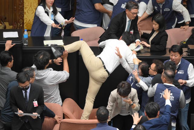 <p>Taiwan’s ruling Democratic Progressive Party (DPP) lawmaker Kuo Kuo Wen (C) tries jumping onto the desk during the voting for a Parliament reform bill</p>