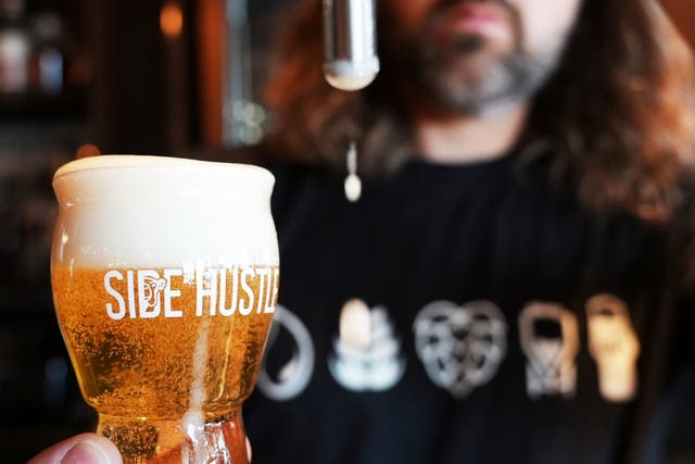 <p>Mitchell Dougherty, the brewmaster at Side Hustle Brews and Spirts, pours a pint of beer at their brew pub in Abu Dhabi, United Arab Emirates</p>