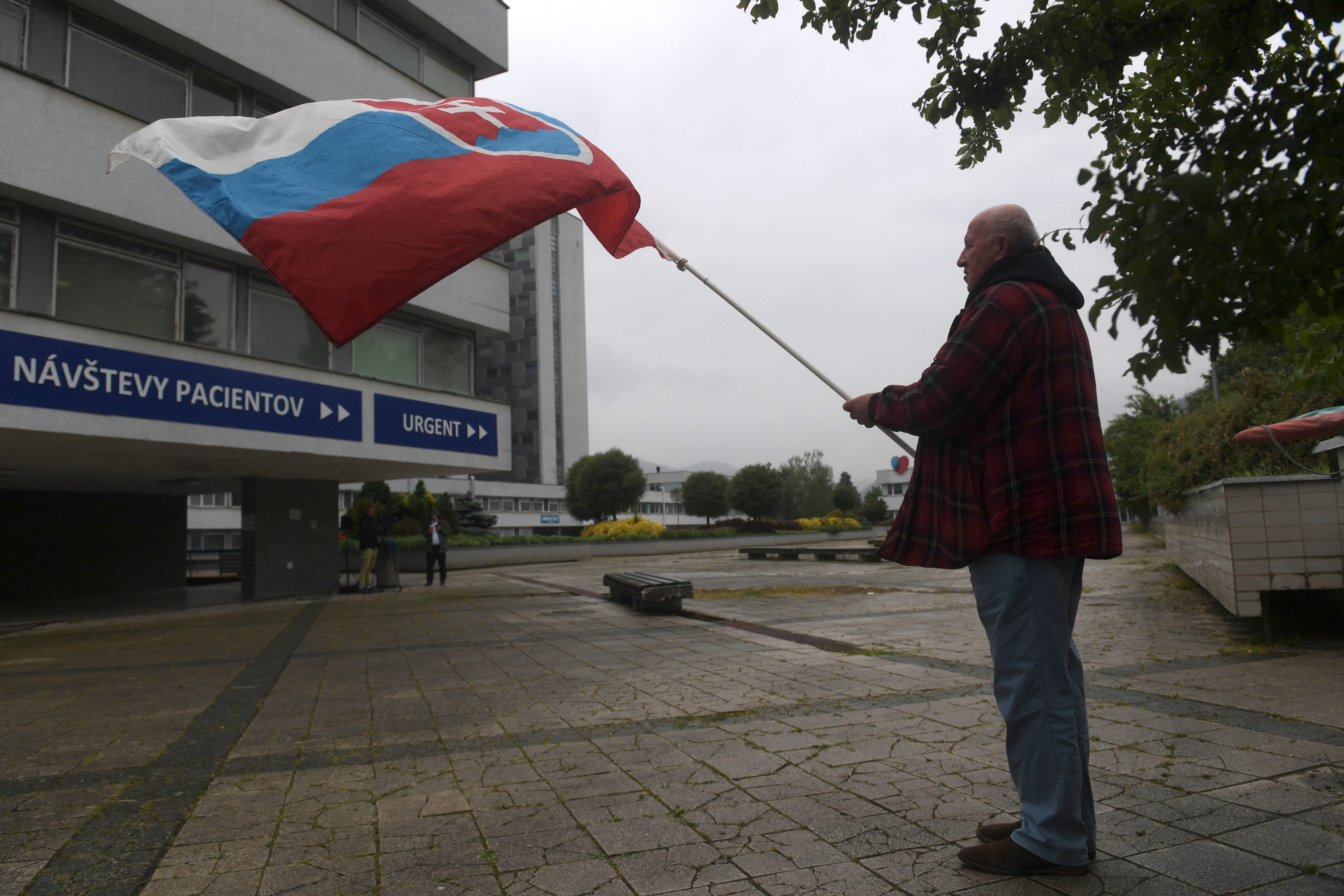 A man waves the Slovakian flag outside the hospital in Banska Bystrica where Mr Fico is being treated