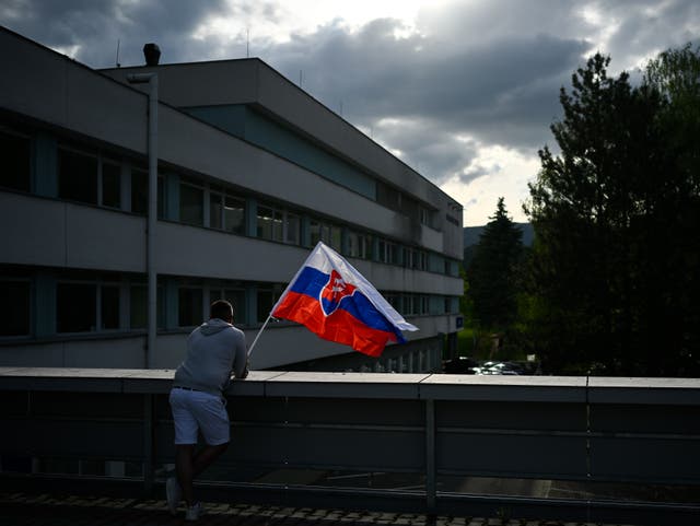 <p>A man waves Slovakia’s flag outside the hospital in Banska Bystrica where Robert Fico is being treated</p>