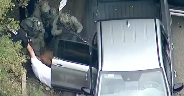 <p>SWAT teams pull what appears to be a suspect from his vehicle after a deadly shooting earlier that day </p>