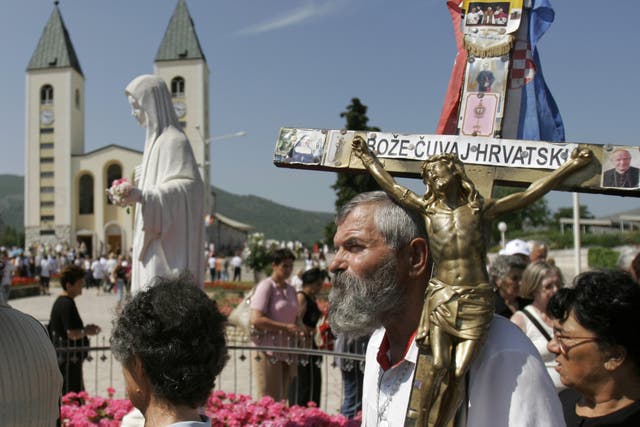 <p>Pilgrims walk around a statue of the Blessed Virgin Mary near the church of St James in Medjugorje, Bosnia and Herzegovina</p>