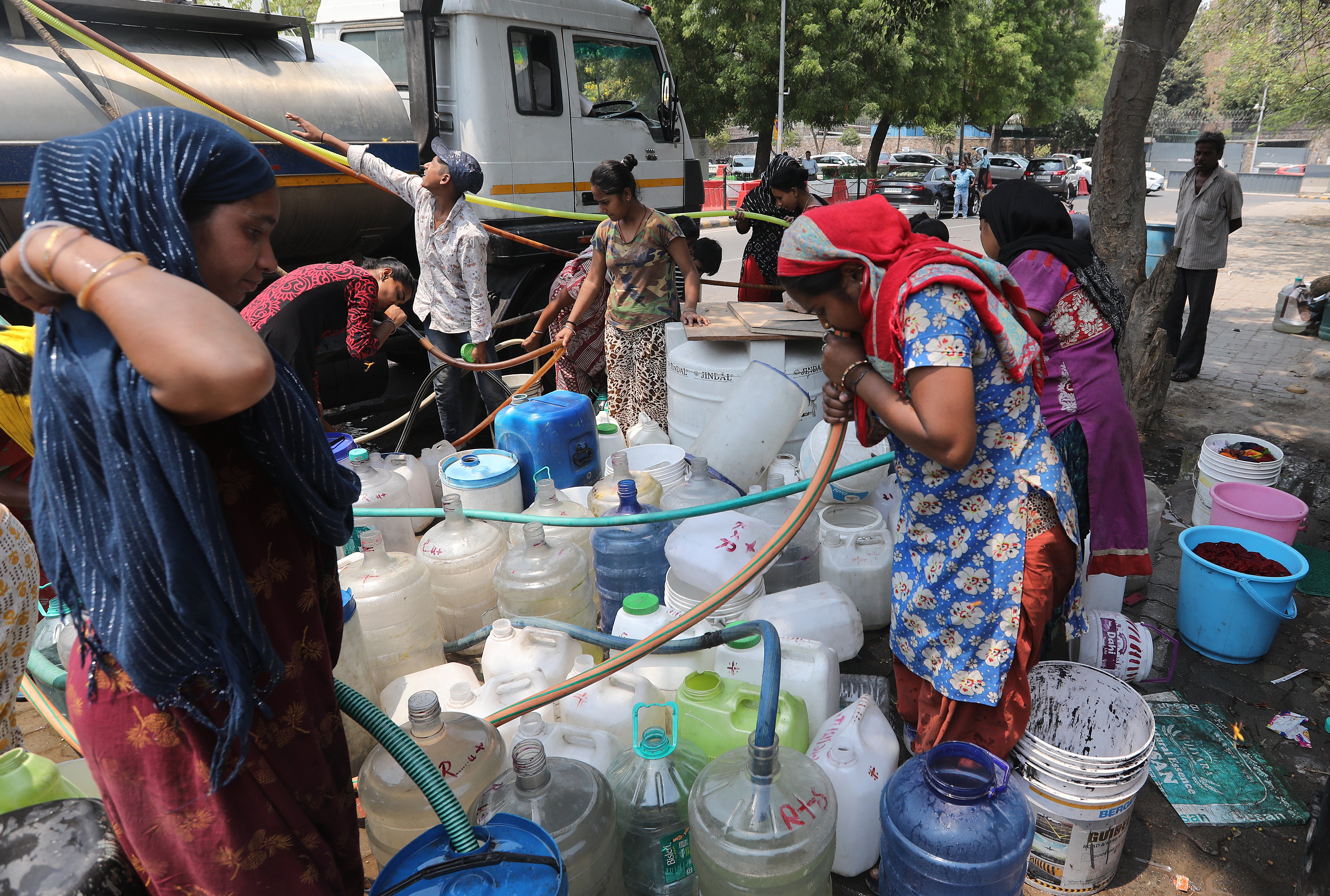 People fill up canisters and containers with water from a tanker at a makeshift settlement in Chankyapuri in New Delhi