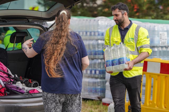 <p>South West Water staff and volunteers distribute water to the public at a water collection point on May 18,</p>
