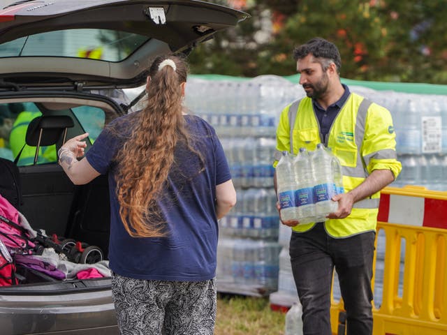 <p>South West Water staff and volunteers distribute water to the public at a water collection point on May 18,</p>